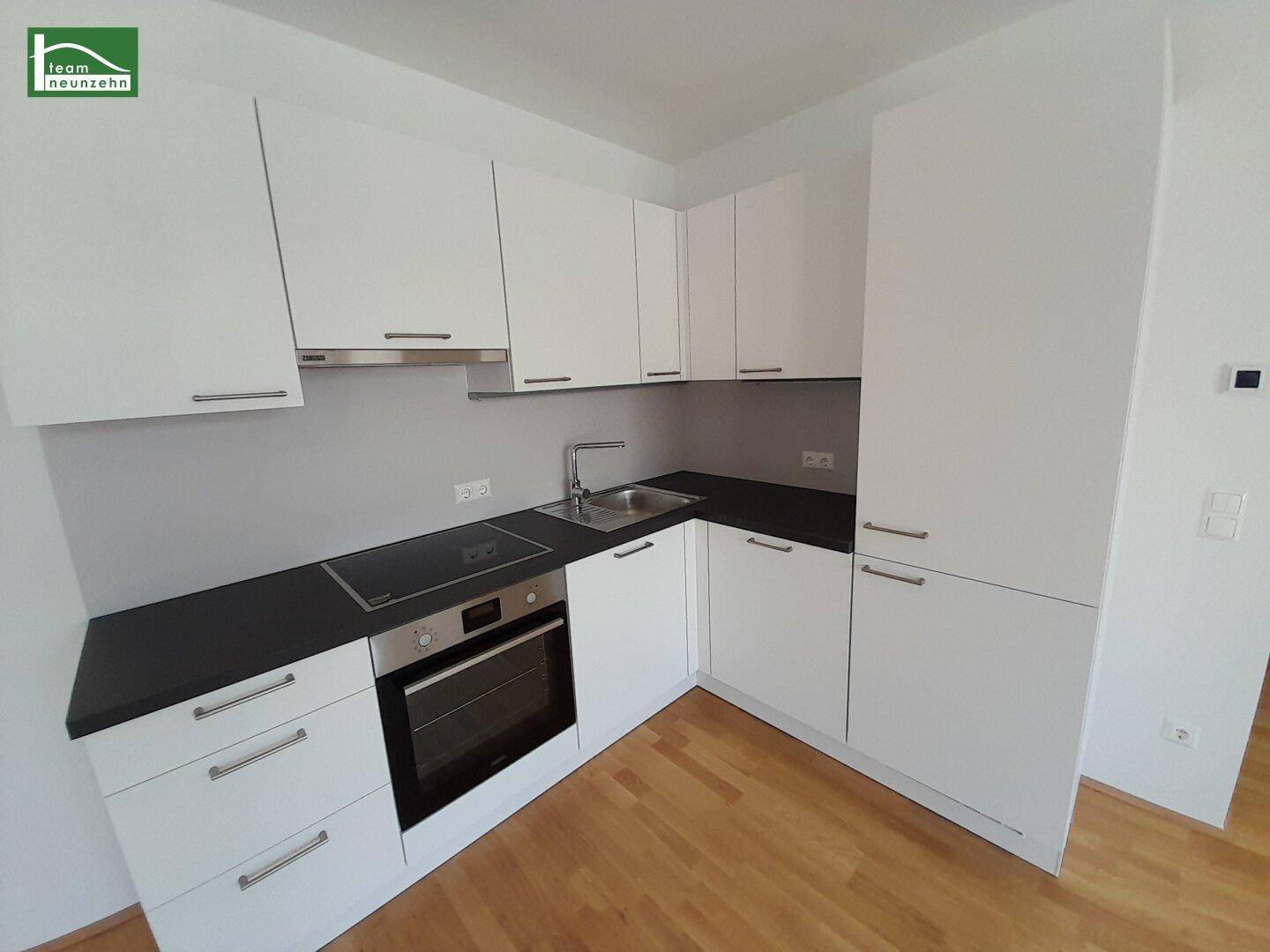 Detailansicht der modernen Einbauküche mit weißen Schränken, Induktionskochfeld und Backofen.
