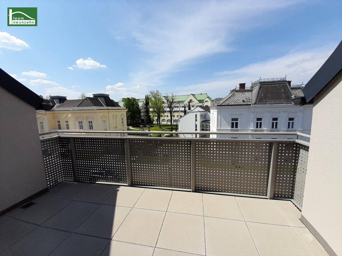 Heller Balkon mit Fliesenboden und weitem Blick auf die umliegenden Gebäude und Grünflächen.