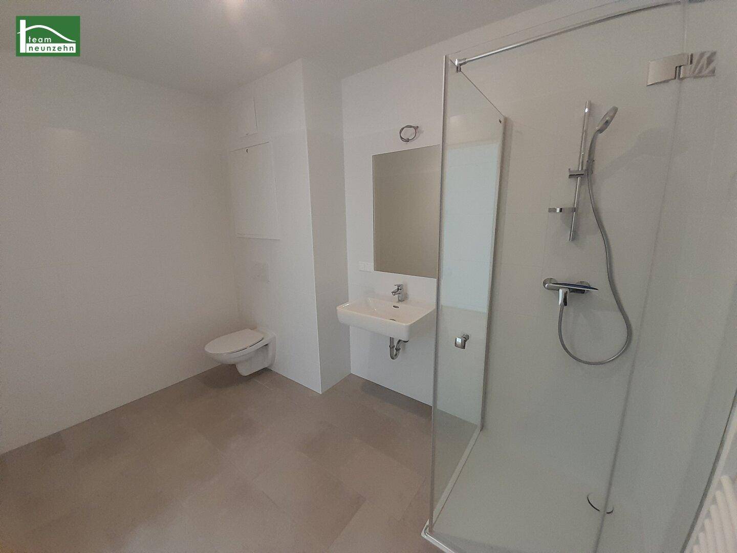 Modernes Badezimmer mit begehbarer Dusche, wandhängendem WC und hellem Fliesenboden.