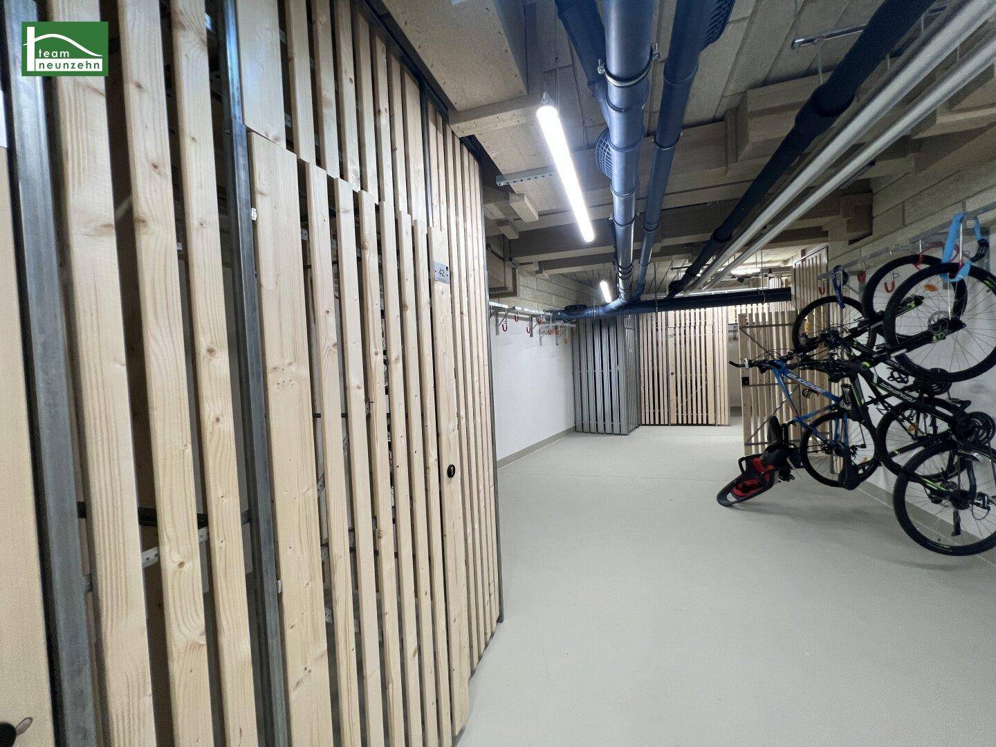 Fahrradabstellraum im Keller mit Holzabtrennungen und Aufhängemöglichkeiten für Fahrräder.
