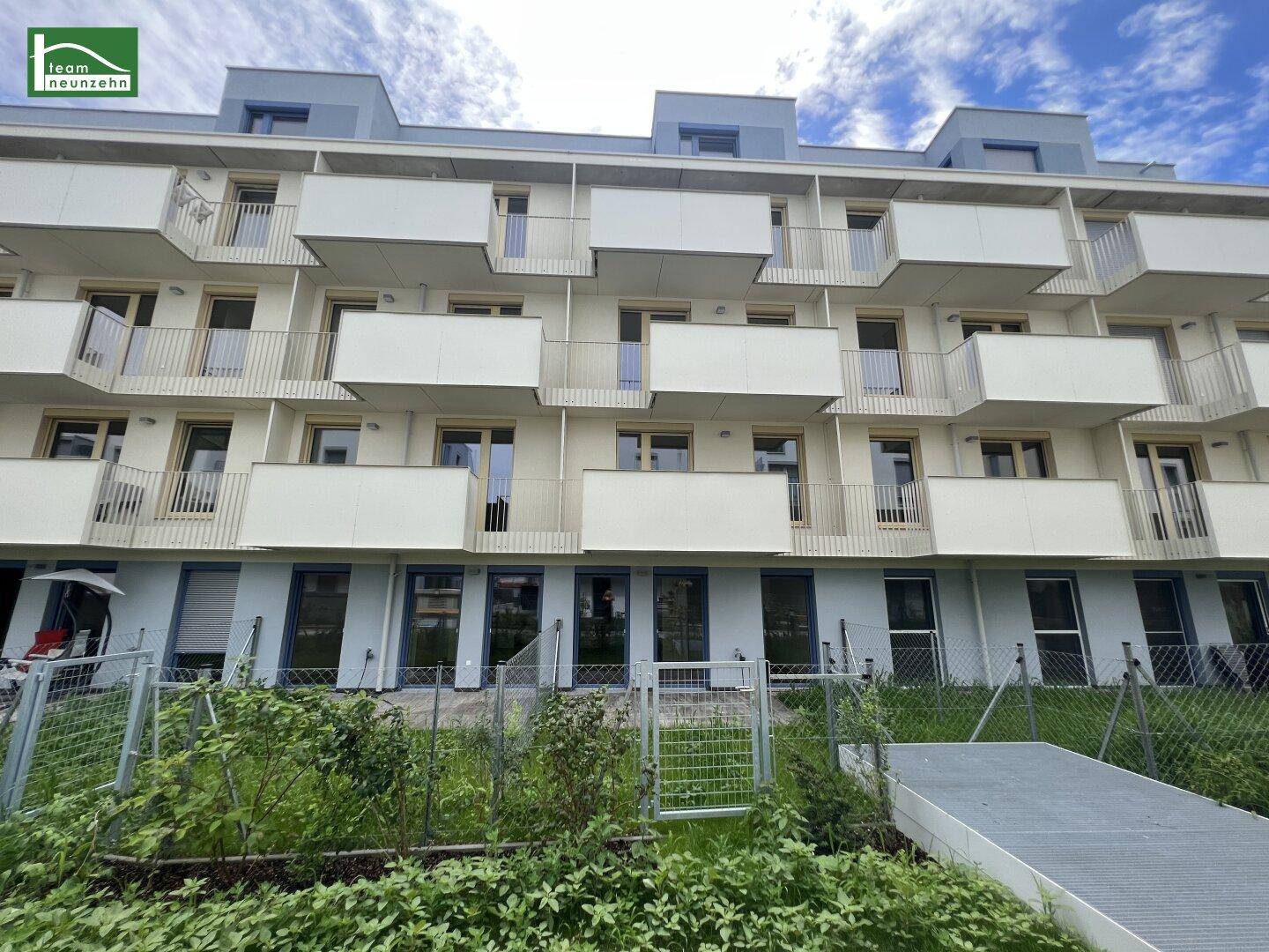 Moderne Wohngebäude mit zahlreichen Balkonen und begrünten Gemeinschaftsflächen im Vordergrund.