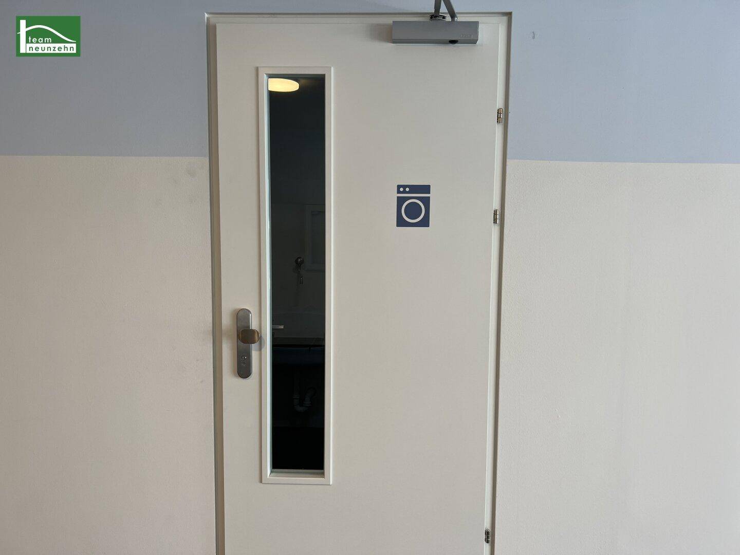 Tür zu einem Gemeinschaftsraum mit Waschmaschinensymbol, wahrscheinlich ein Waschraum.