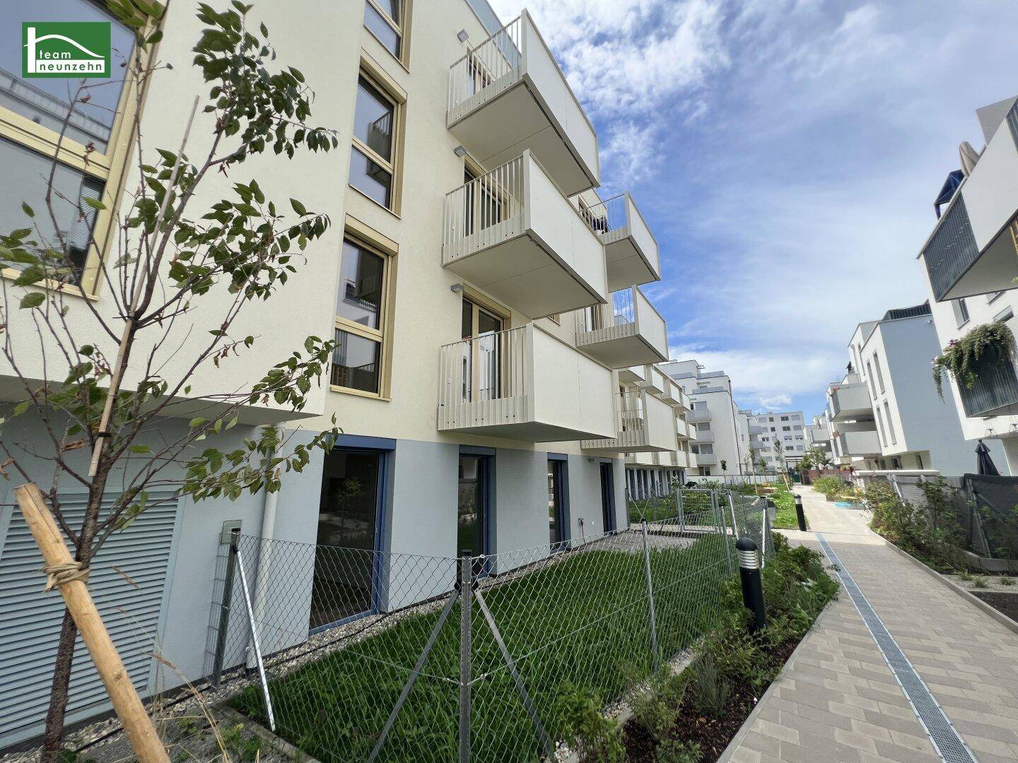 Moderne Wohngebäude mit Balkonen und einem gepflegten Gehweg entlang der Grünflächen.