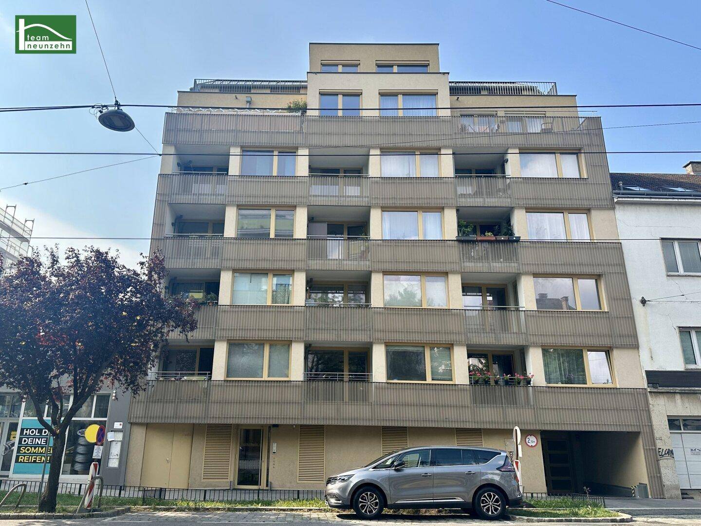 Moderne Fassade eines Mehrfamilienhauses mit zahlreichen Balkonen und großen Fenstern.