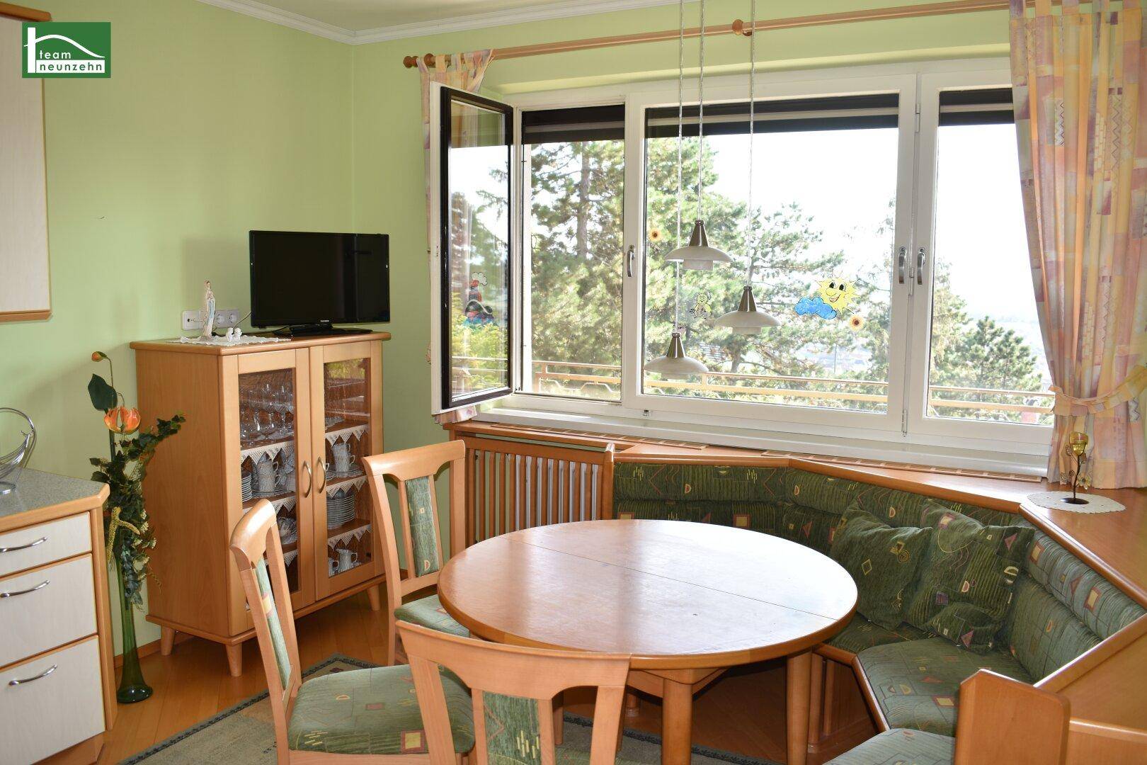 Gemütlicher Essbereich mit Eckbank, Holztisch und weitem Ausblick durch große Fenster.