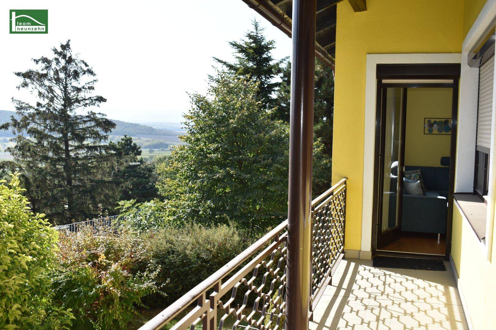 Balkon mit schmiedeeisernem Geländer und weitem Blick über die grüne Landschaft.