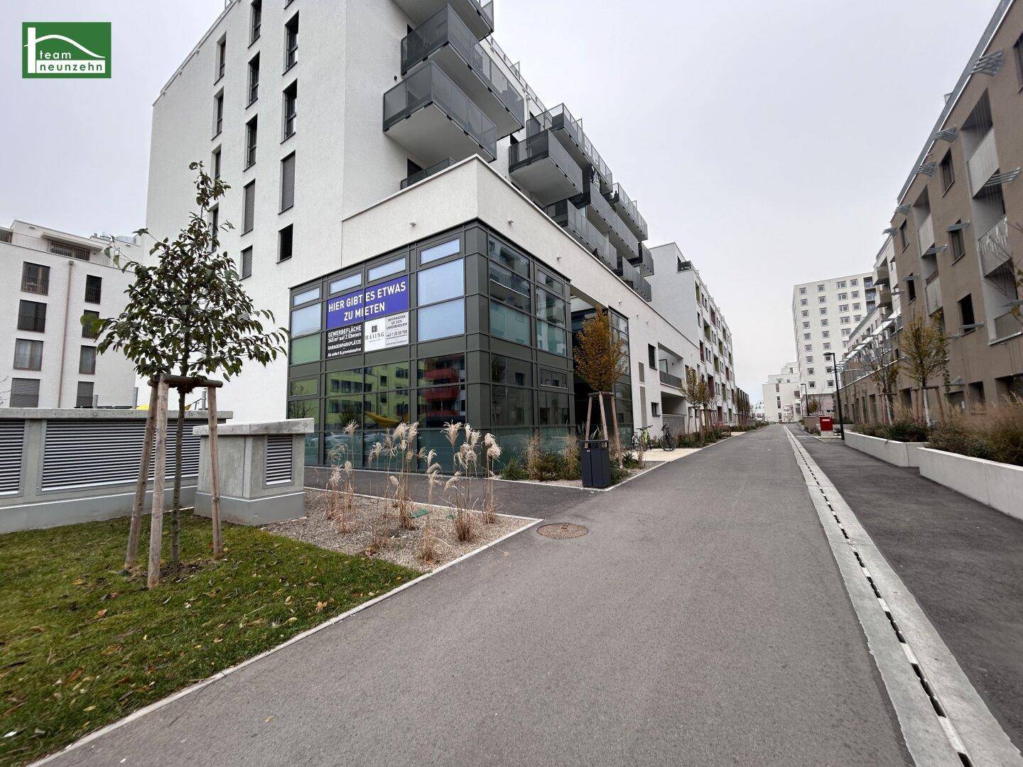 Moderne Wohn- und Geschäftsgebäude entlang einer Straße mit gepflegter Außenanlage.