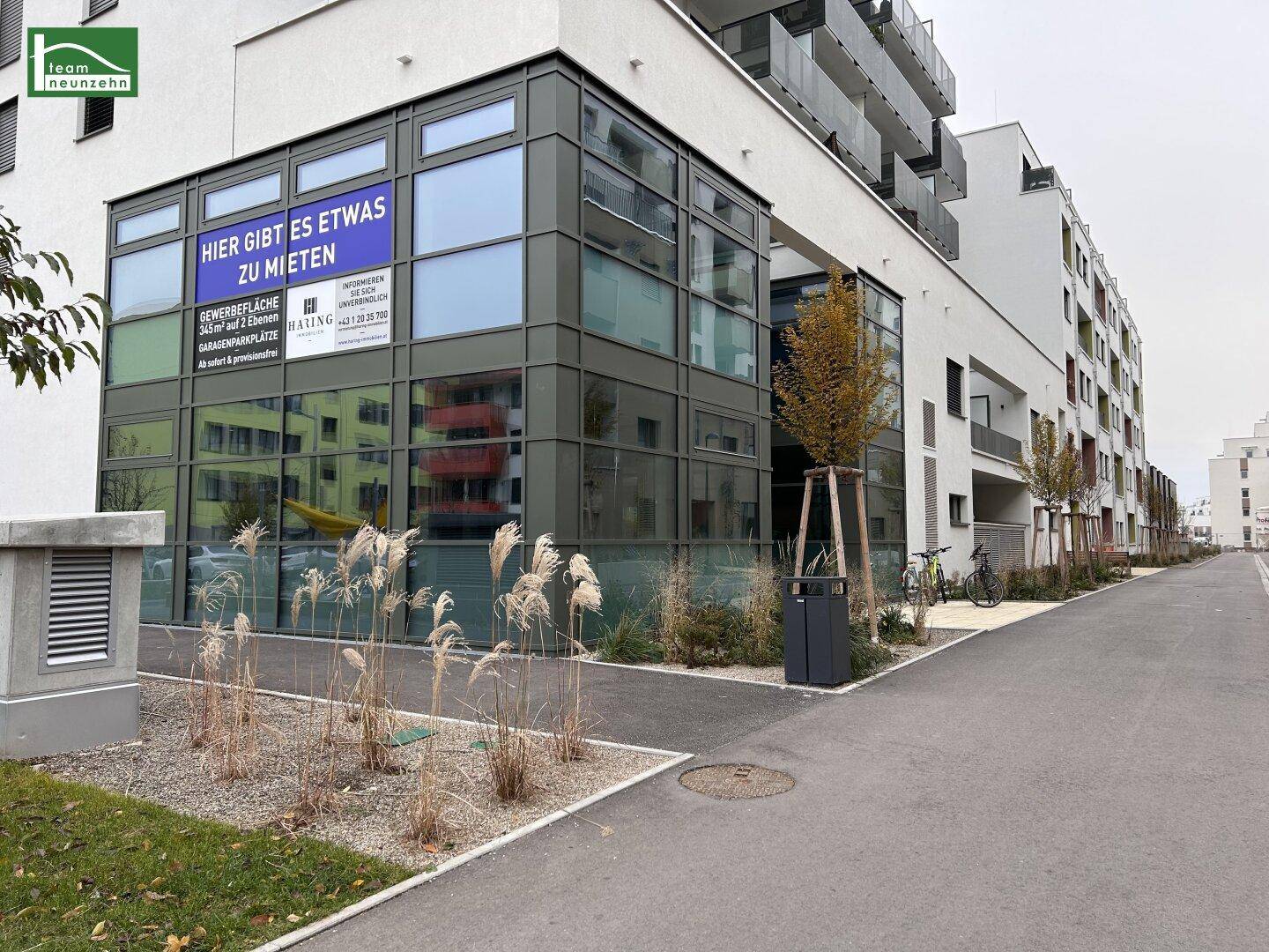 Moderne Gebäudefassade mit großen Fenstern und einem "Zu vermieten"-Schild im Erdgeschoss.