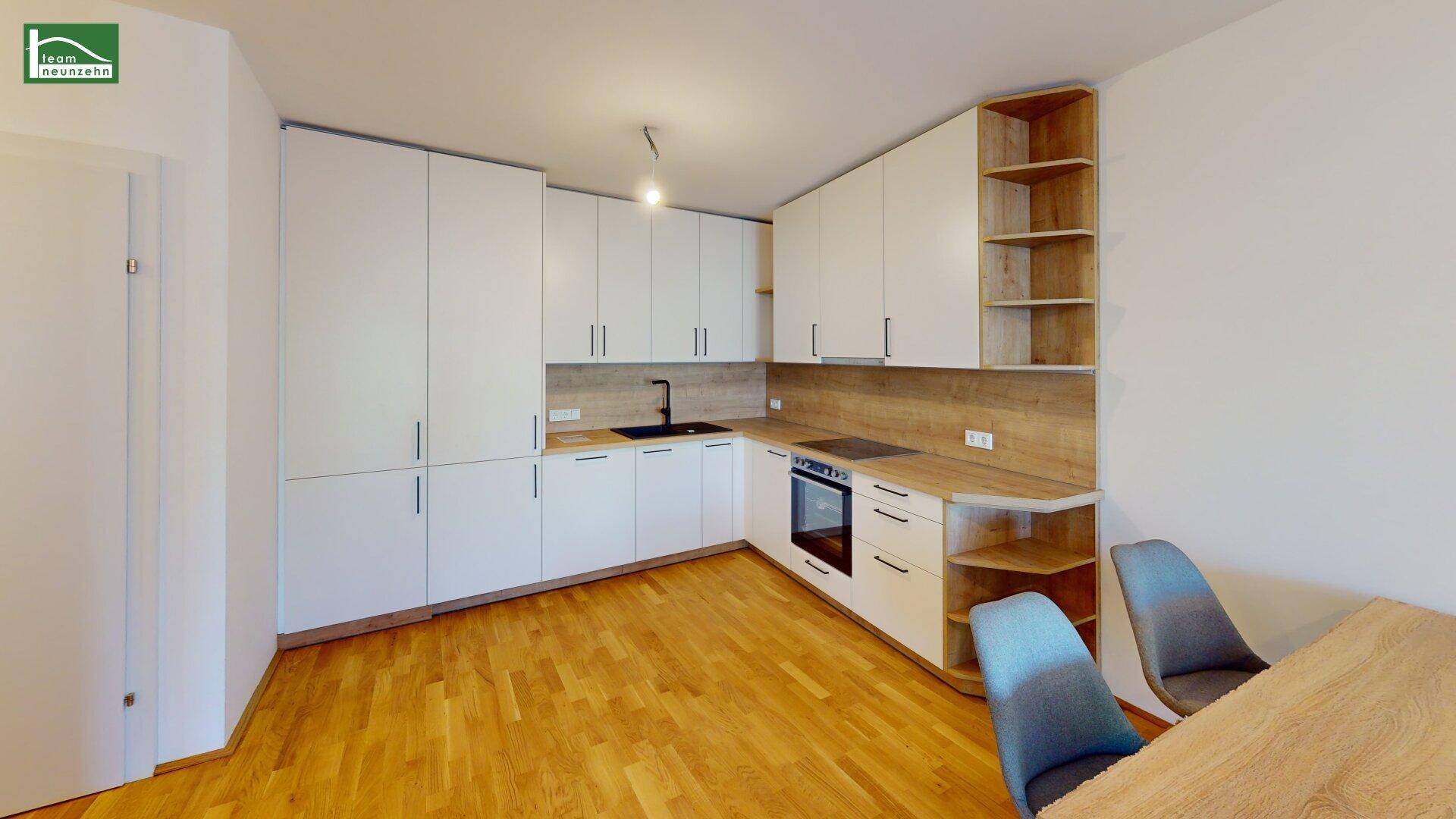 Moderne Küche mit weißen Schränken, Holz-Arbeitsplatten und integrierten Geräten in hellem Design.