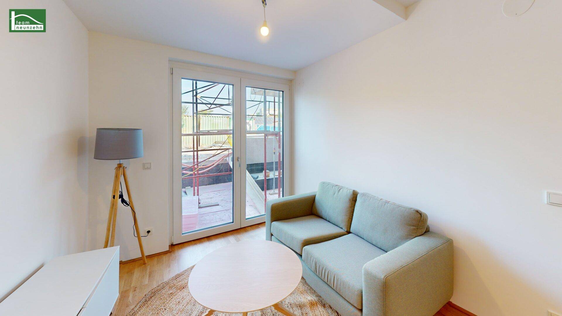 Gemütlicher Wohnbereich mit Sofa, Couchtisch und großen Fenstertüren, die viel Licht hereinlassen.