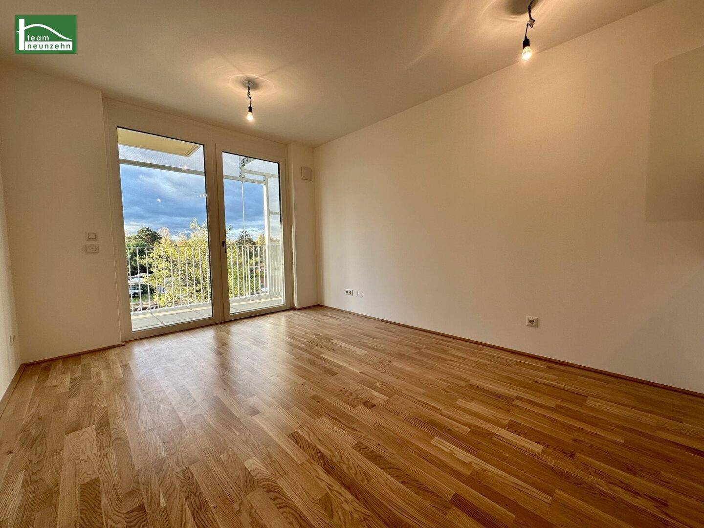 Geräumiges, leeres Zimmer mit Holzboden und direktem Zugang zu einem Balkon.
