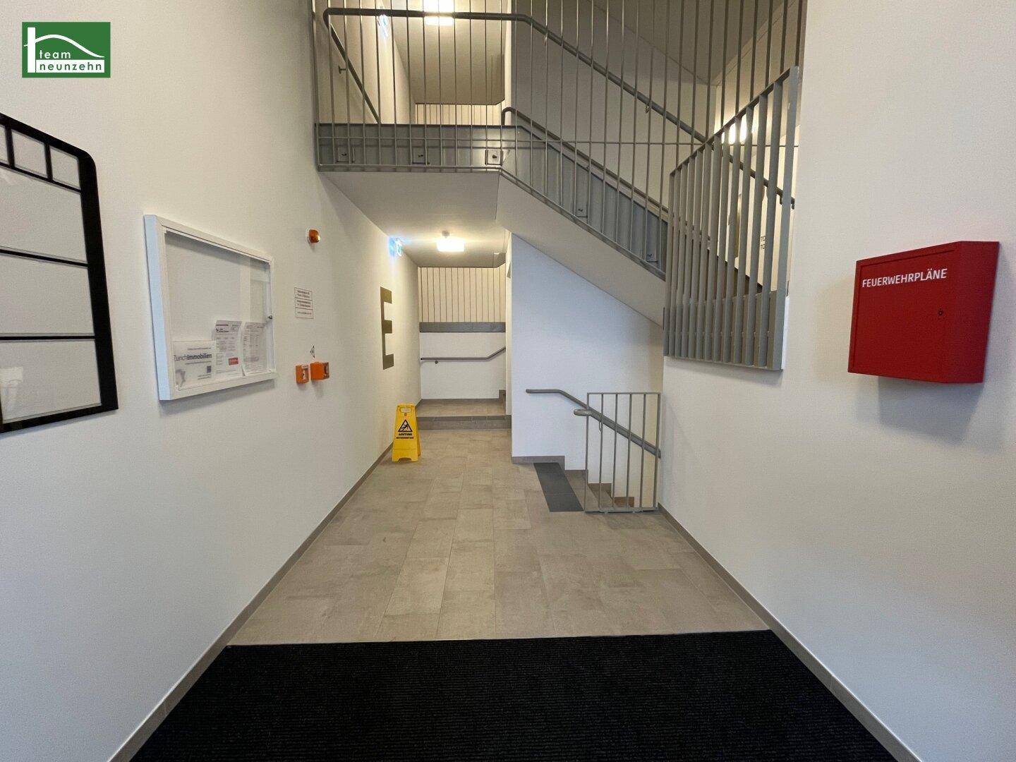 Treppenhaus mit Metallgeländer und Fliesenboden, das die verschiedenen Etagen des Gebäudes verbindet.