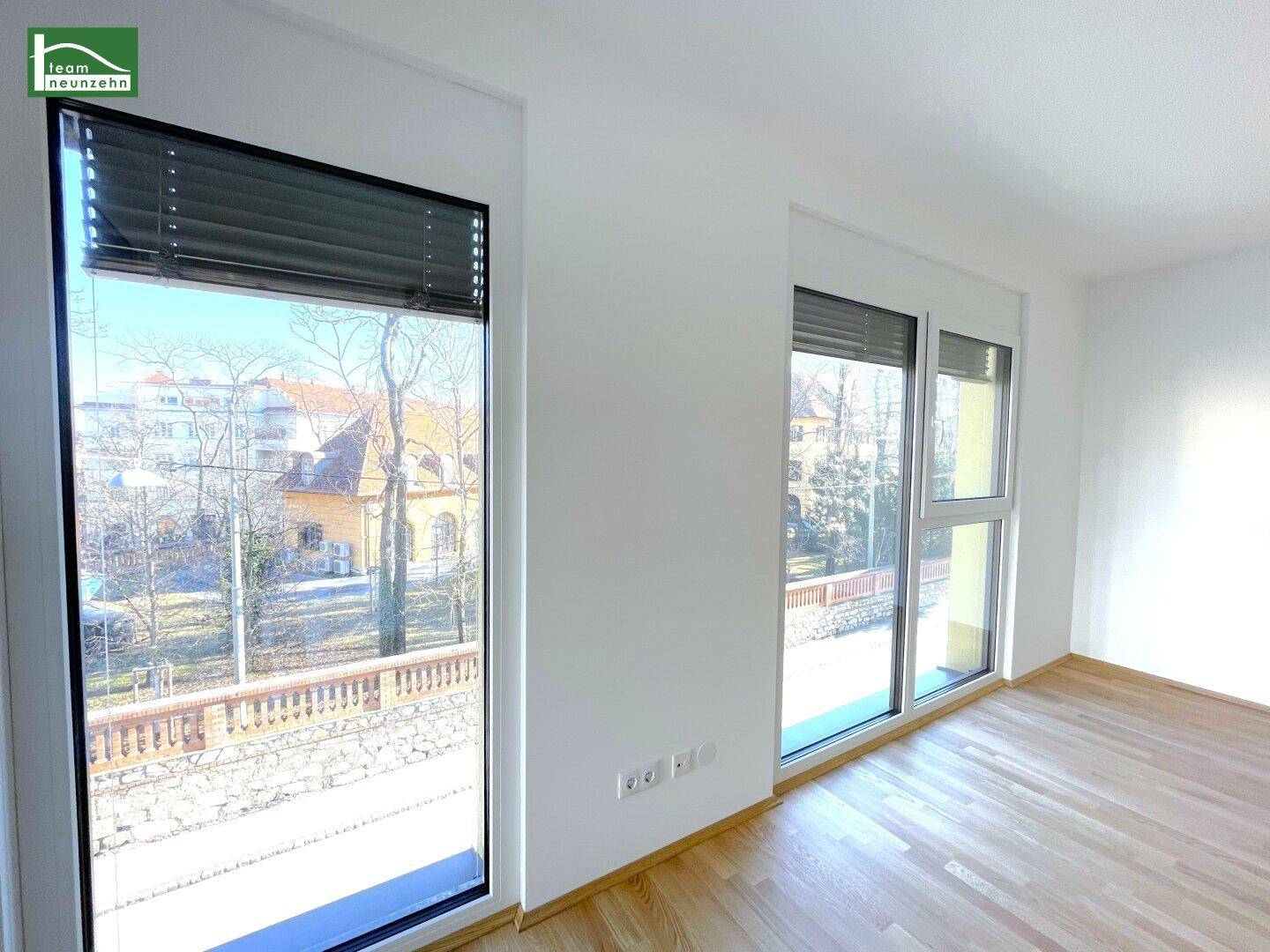 Heller Raum mit großen Fenstern, Parkettboden und Blick ins Grüne, ideal für Wohn- oder Schlafzimmer.