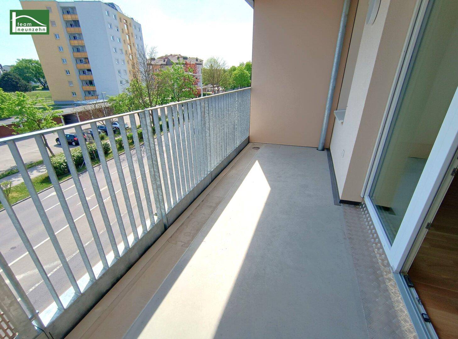 Heller Balkon mit Metallgeländer und Blick auf die Straße sowie umliegende Gebäude.
