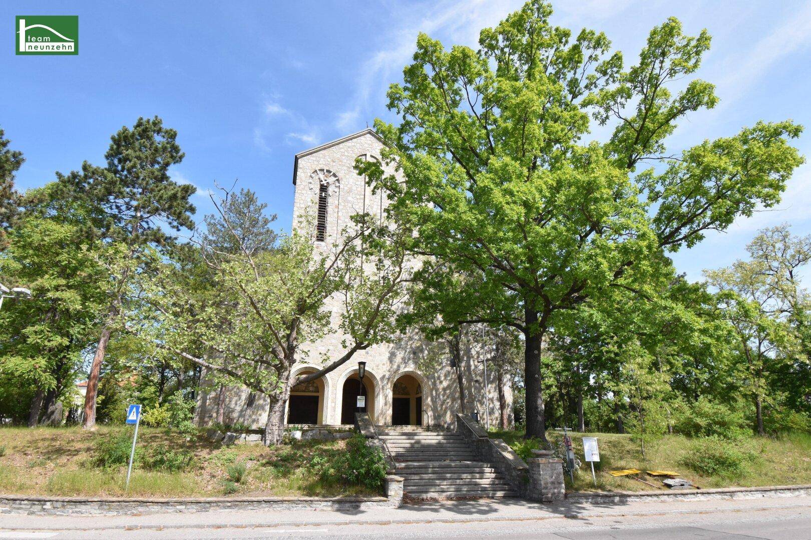 Weitläufige Ansicht der Steinkirche mit Treppenaufgang und üppiger Vegetation.