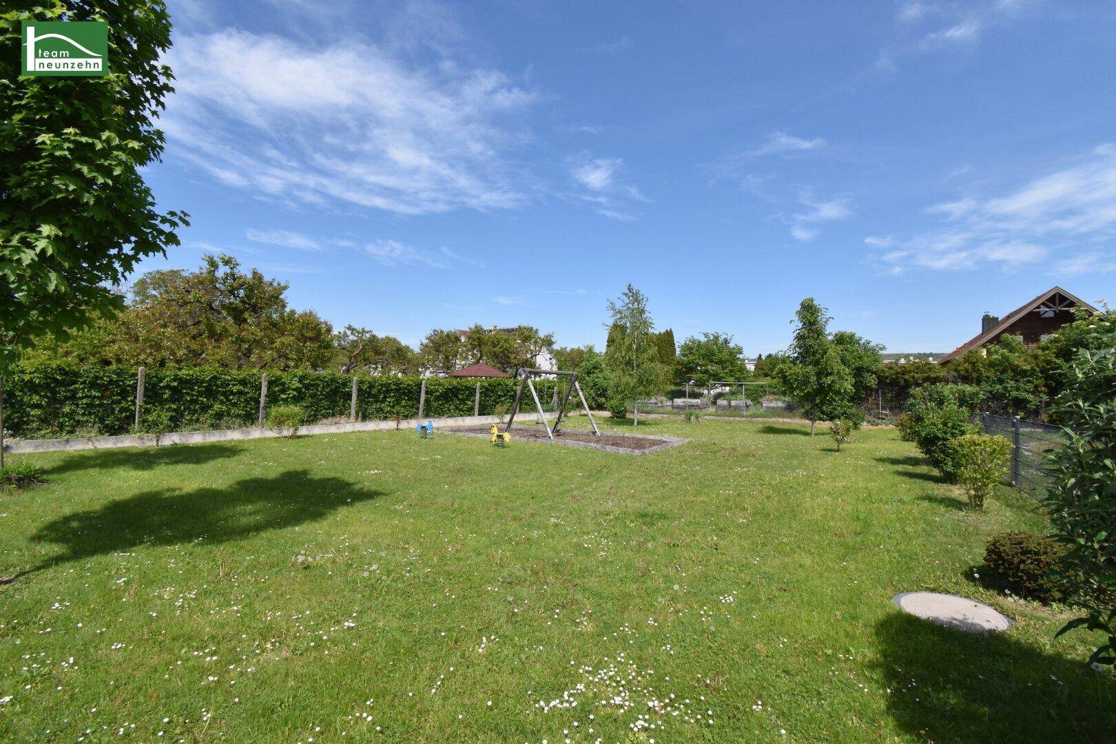 Großer Garten mit Rasenfläche, Schaukel und viel Grün, ideal für Familien.