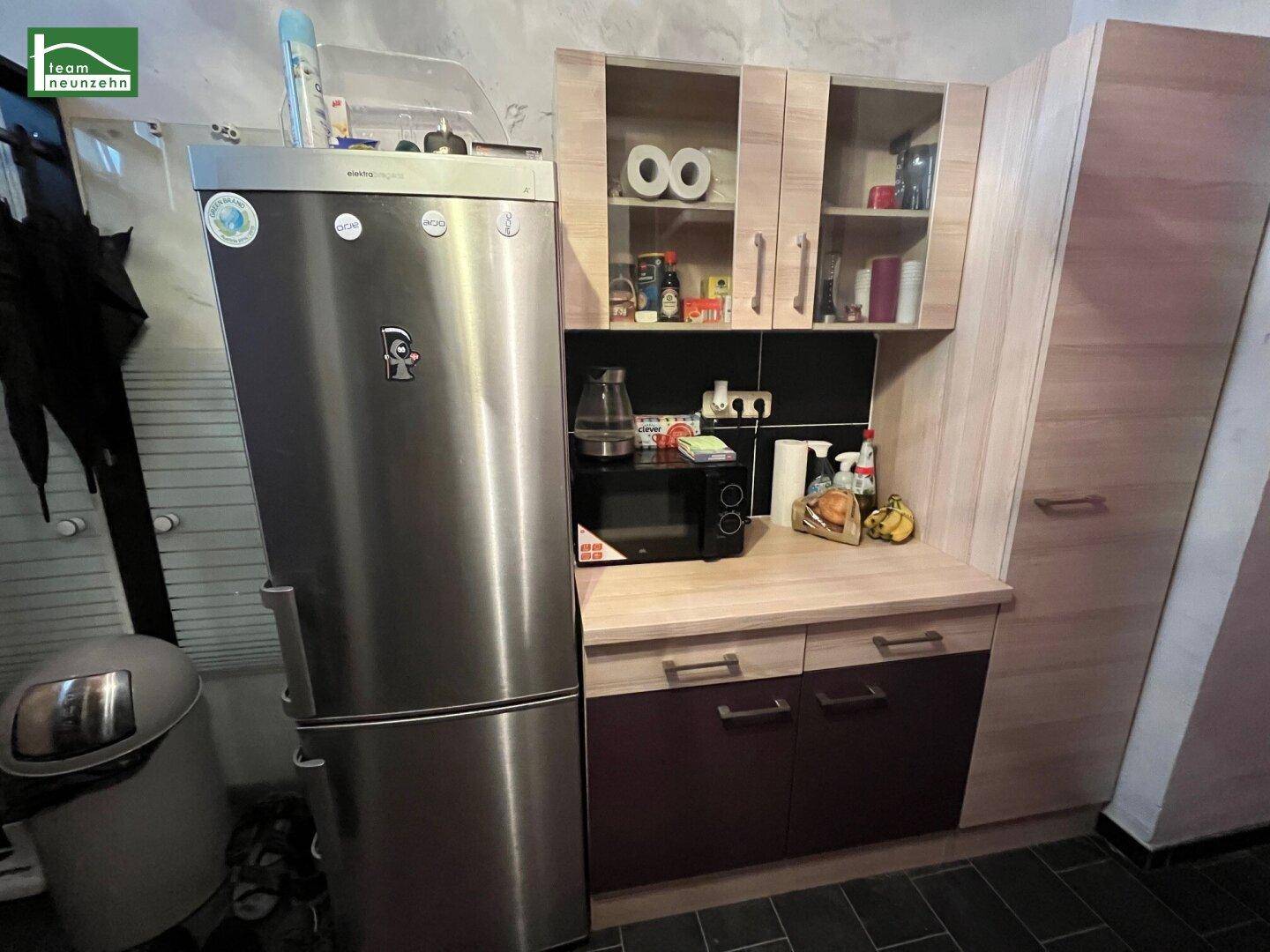 Küchenzeile mit Kühlschrank, Mikrowelle und Holzschränken, die eine funktionale Ausstattung bietet.