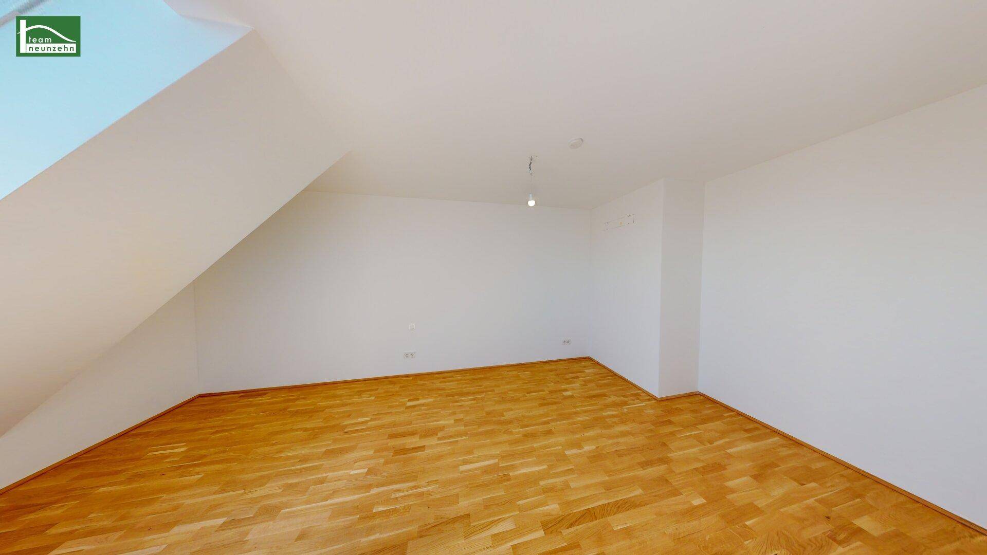 Schlafzimmer im Dachgeschoss mit schrägen Wänden und hellem Parkettboden, bietet viel Gestaltungspotenzial.