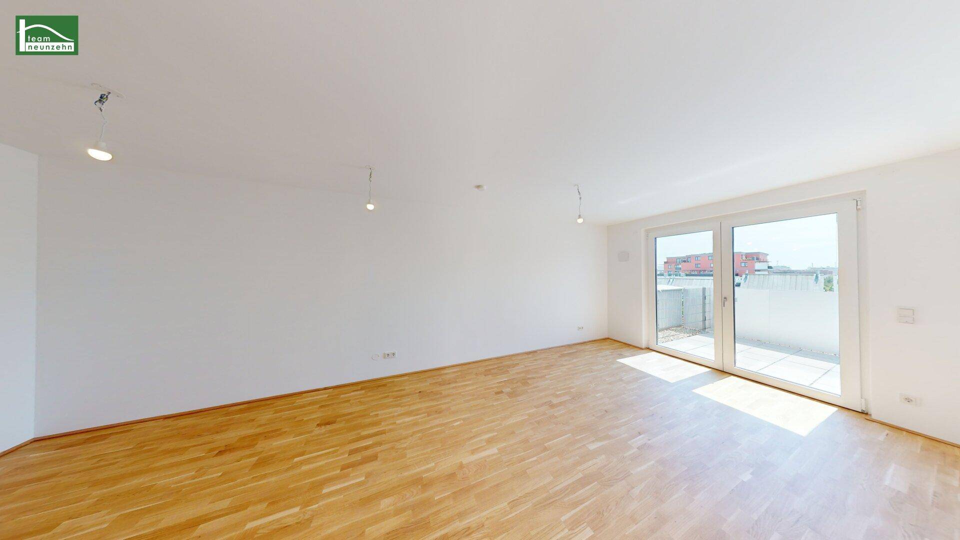 Lichtdurchflutetes Wohnzimmer mit Parkettboden und Zugang zu einem Außenbereich, bietet viel Helligkeit.