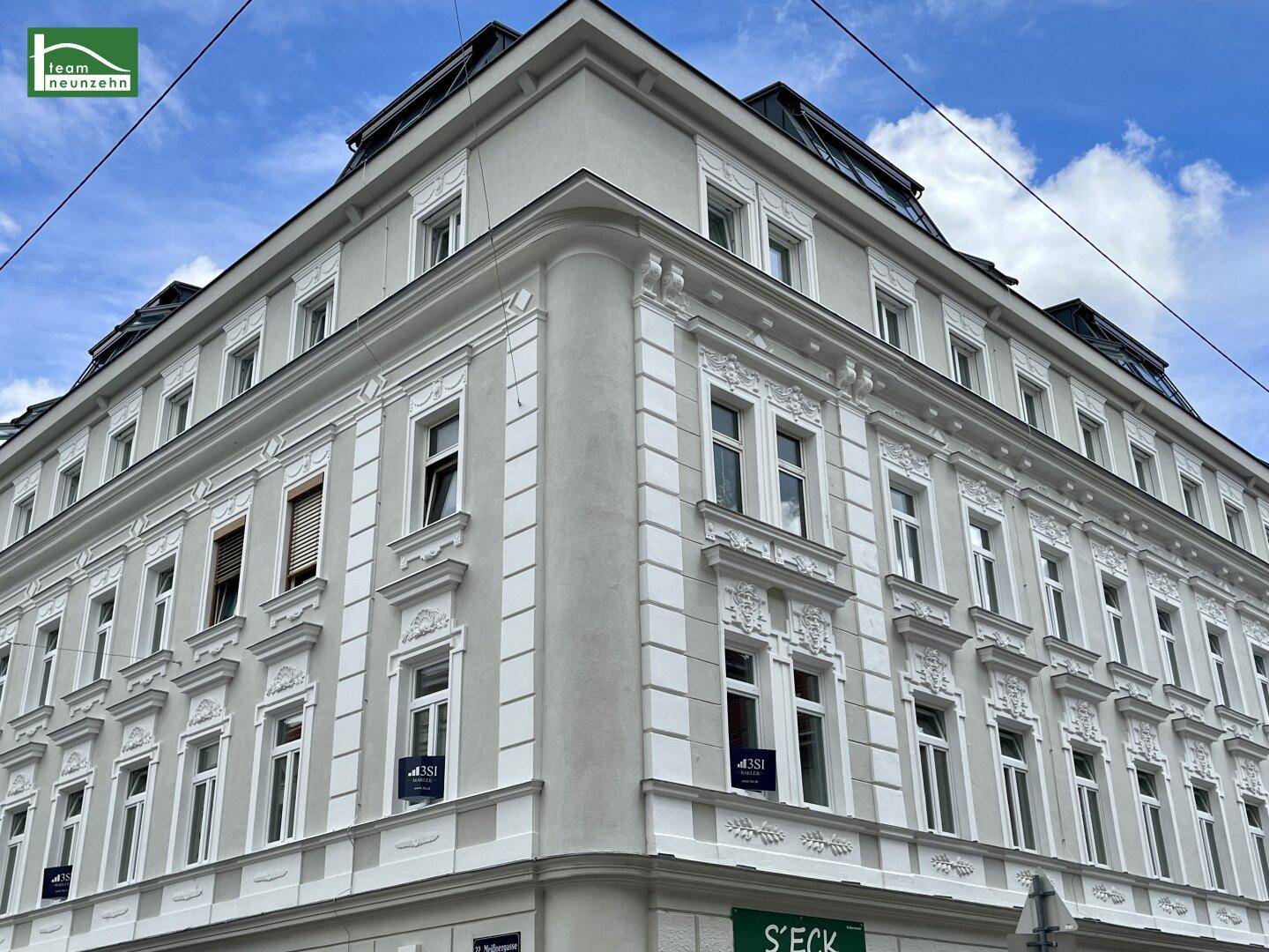 Detailansicht der Gebäudeecke mit klassischer Architektur und dekorativen Fassadenelementen.