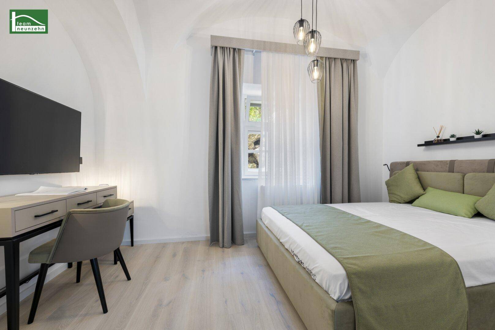 Helles Schlafzimmer mit gewölbter Decke, modernem Bett, Schreibtisch und Fernseher.