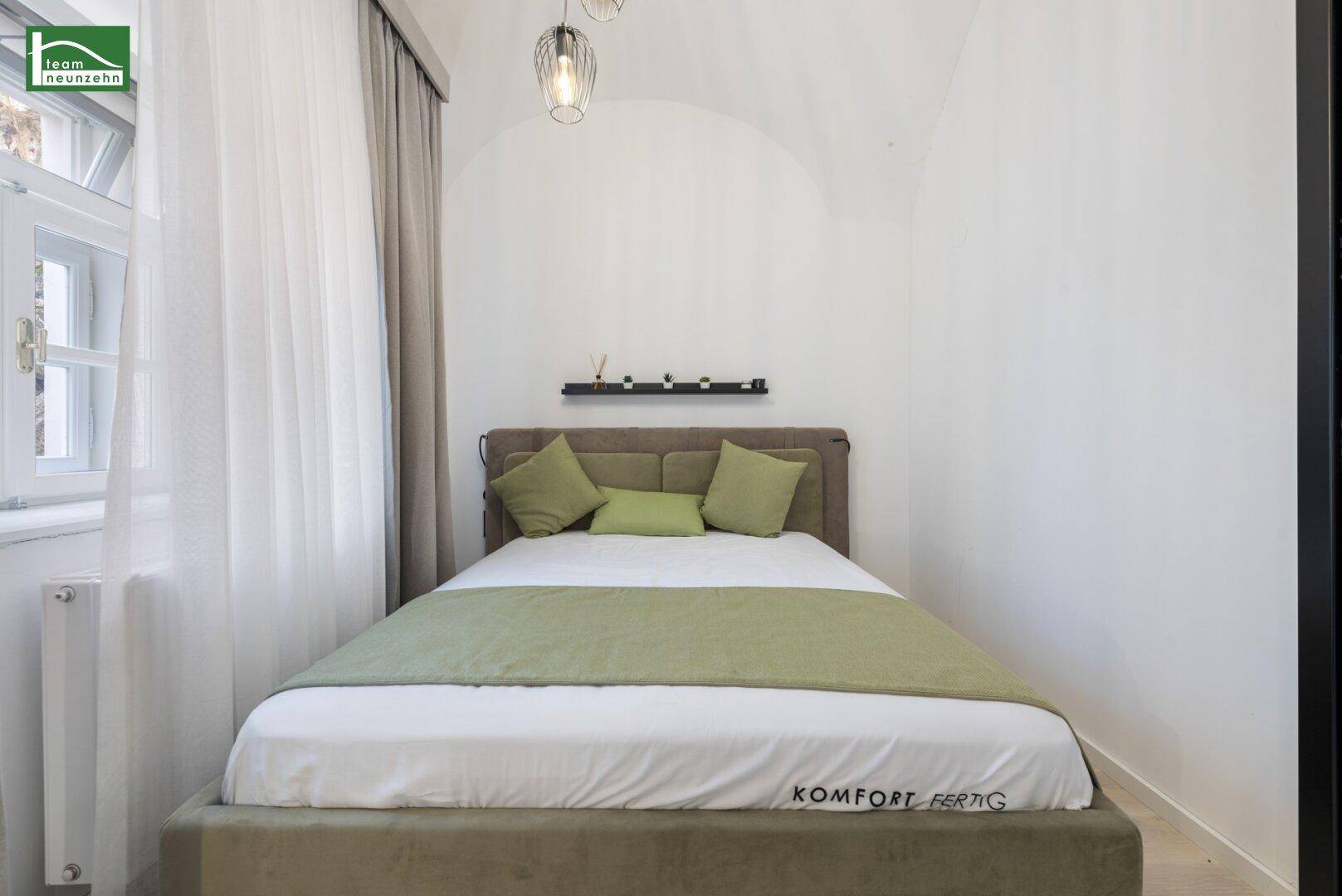 Komfortables Schlafzimmer mit Doppelbett, grünen Akzenten und natürlichem Lichteinfall durch das Fenster.