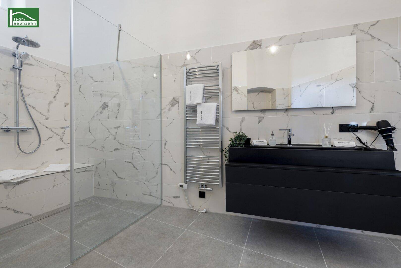 Modernes Badezimmer mit großer Dusche, Doppelwaschbecken und Marmorfliesen.