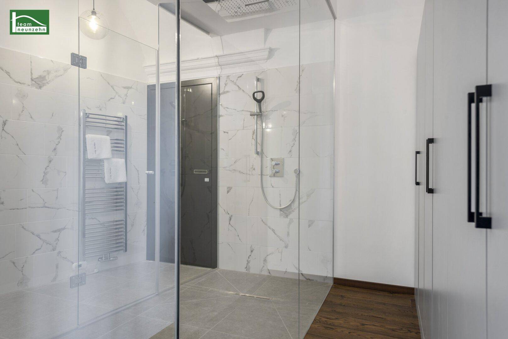Modernes Badezimmer mit großer Glasdusche, Regendusche und Marmorfliesen.