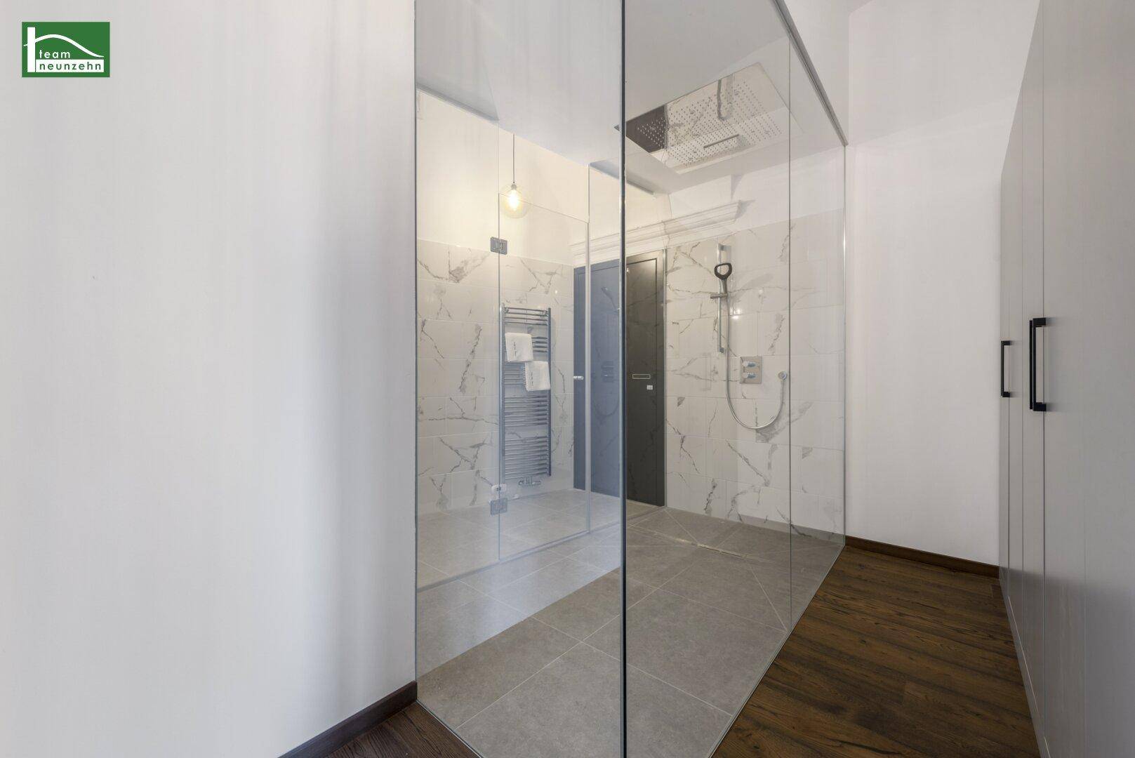 Geräumiges Badezimmer mit großer Glasdusche und modernen Marmorfliesen.
