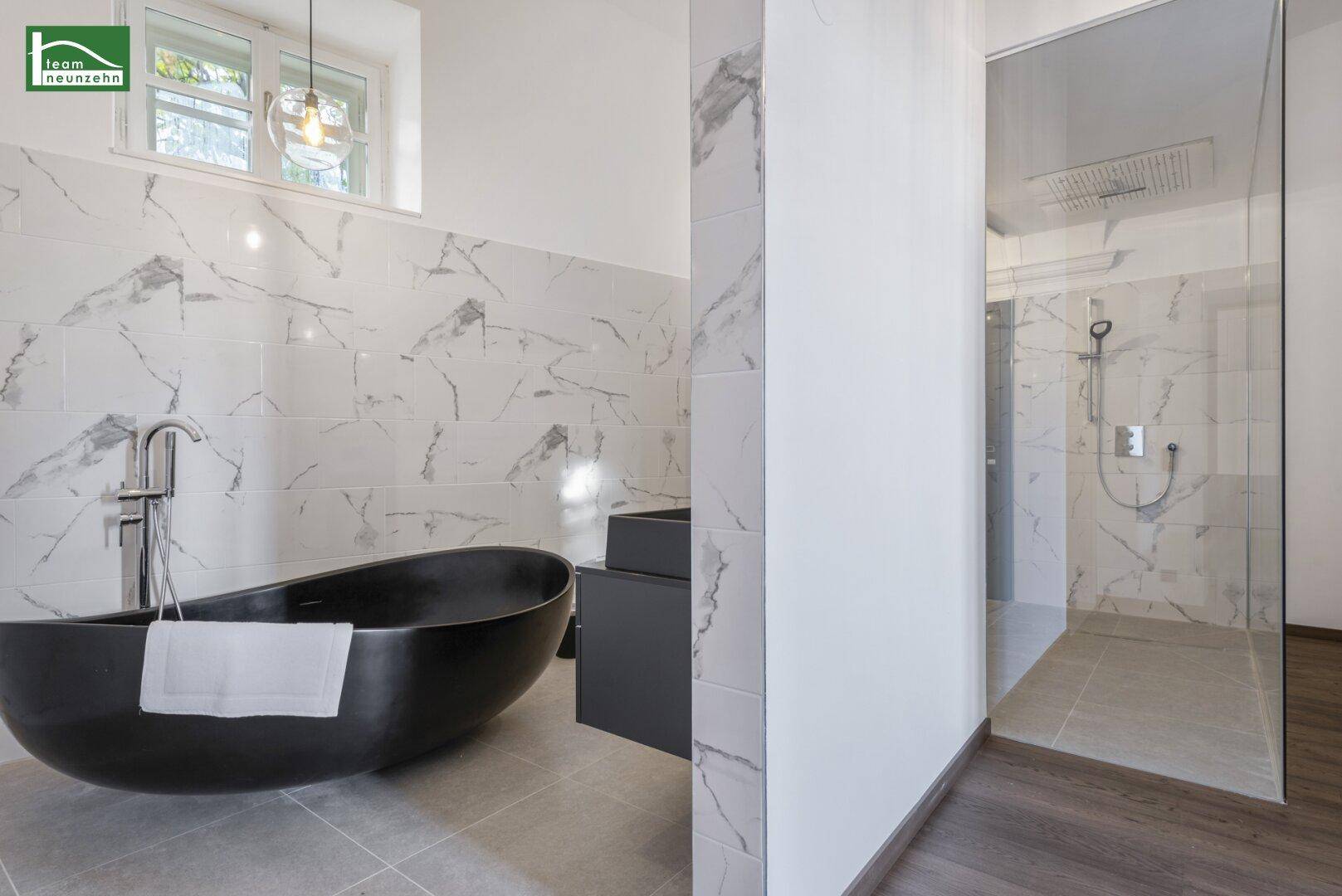 Luxuriöses Badezimmer mit freistehender schwarzer Badewanne und großer Dusche.