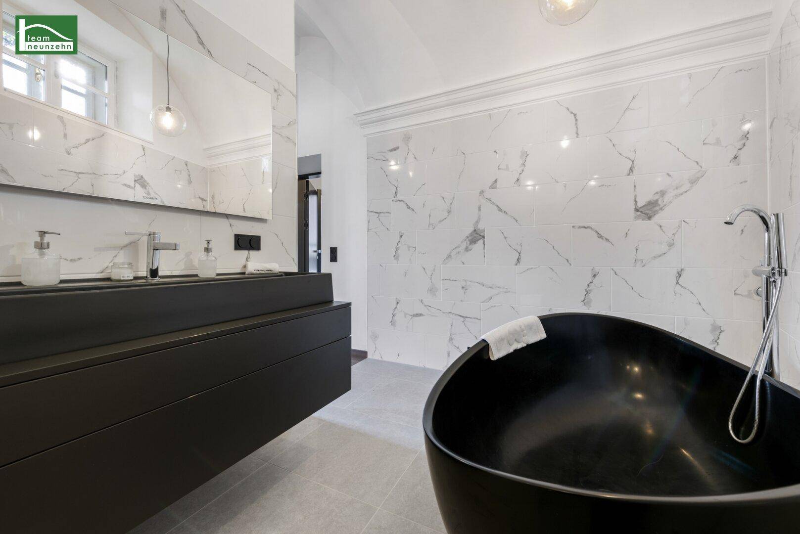Elegantes Badezimmer mit freistehender Badewanne, Doppelwaschbecken und Marmorfliesen.