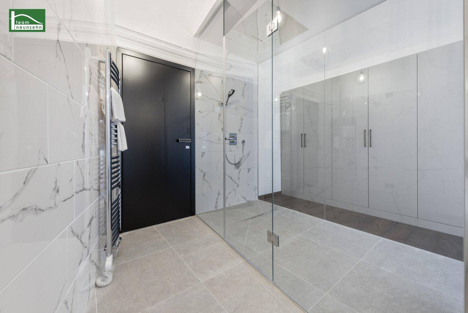 Modernes Badezimmer mit großer Glasdusche, Marmorfliesen und beheiztem Handtuchhalter.