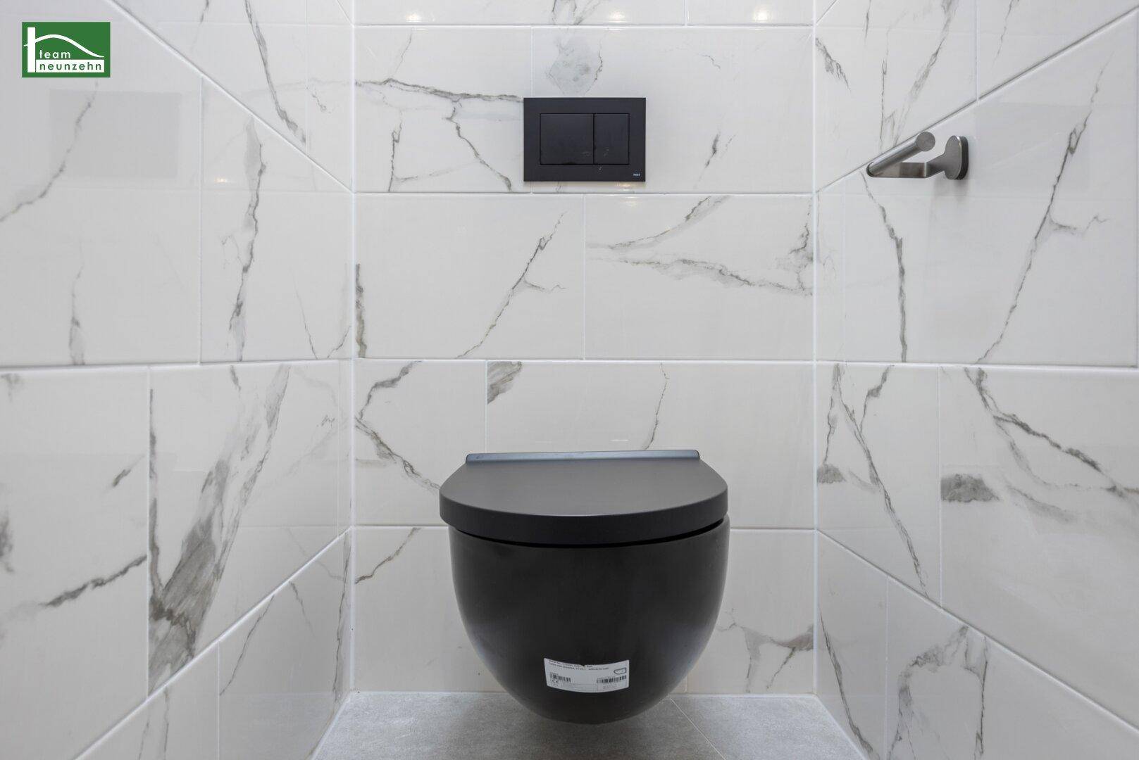 Modernes WC mit schwarzer Wandtoilette und eleganten Marmorfliesen.