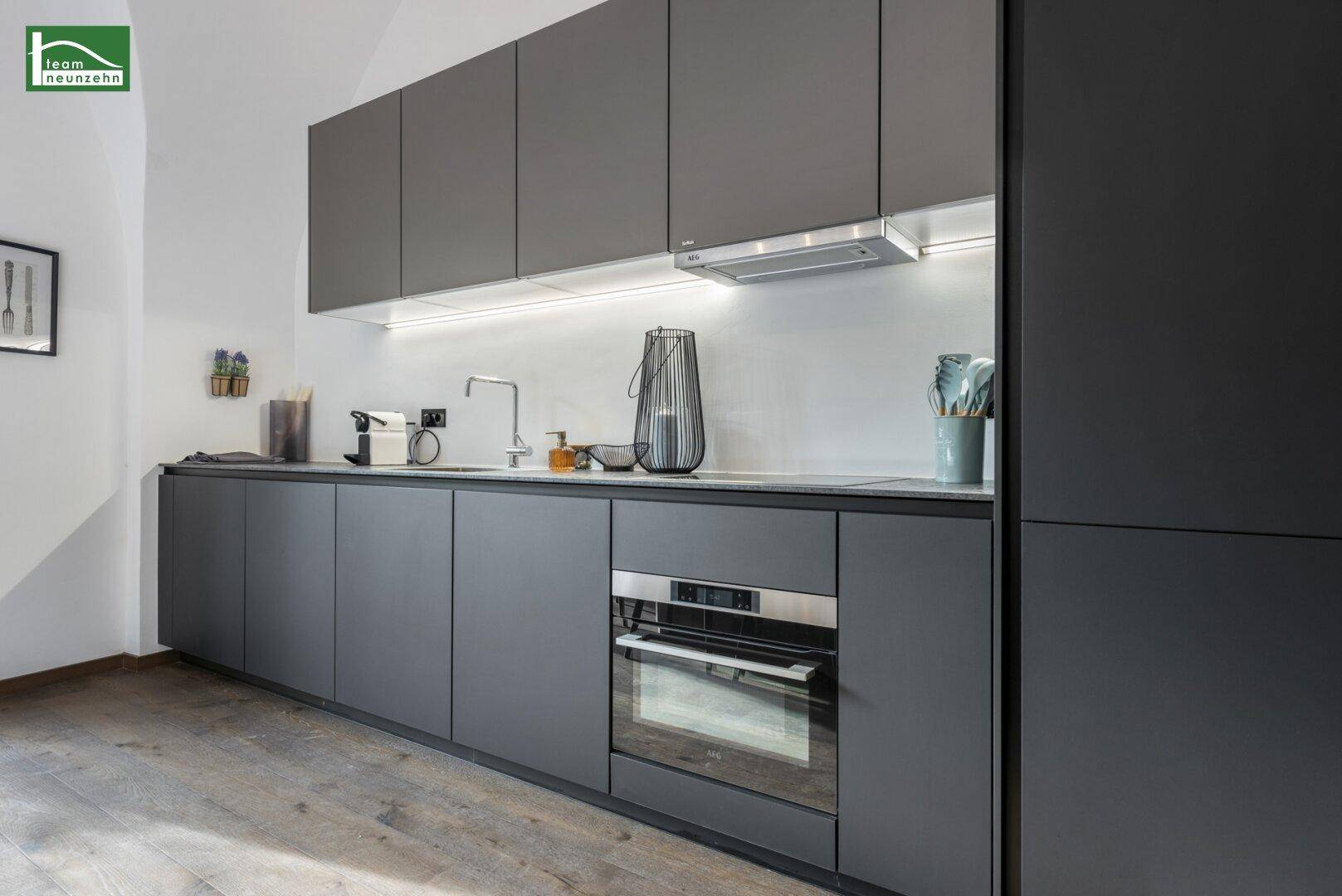 Moderne Einbauküche in Grau mit integrierten Geräten und viel Stauraum.