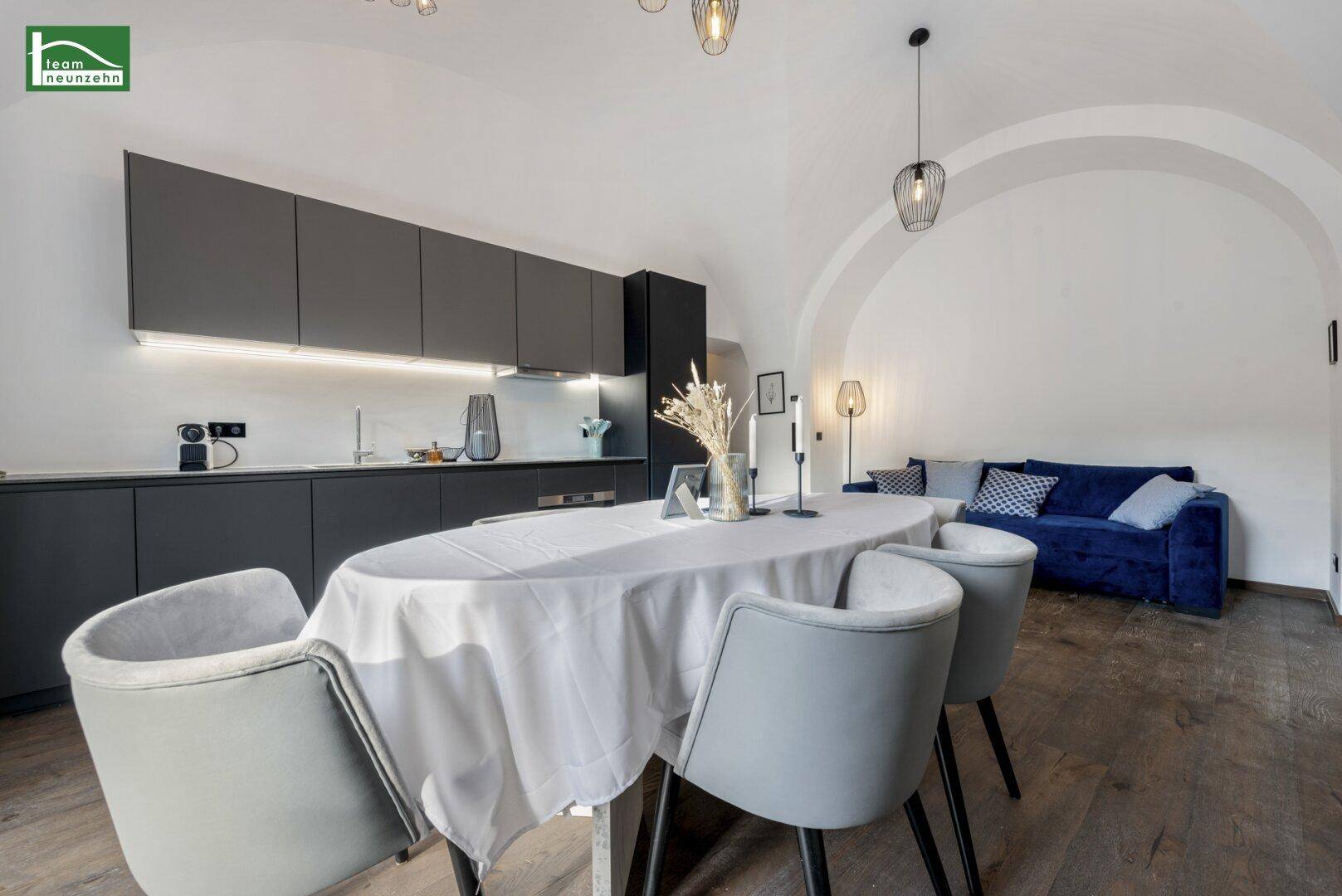 Offener Wohnbereich mit Essplatz, moderner Küche und gemütlichem Sofa.