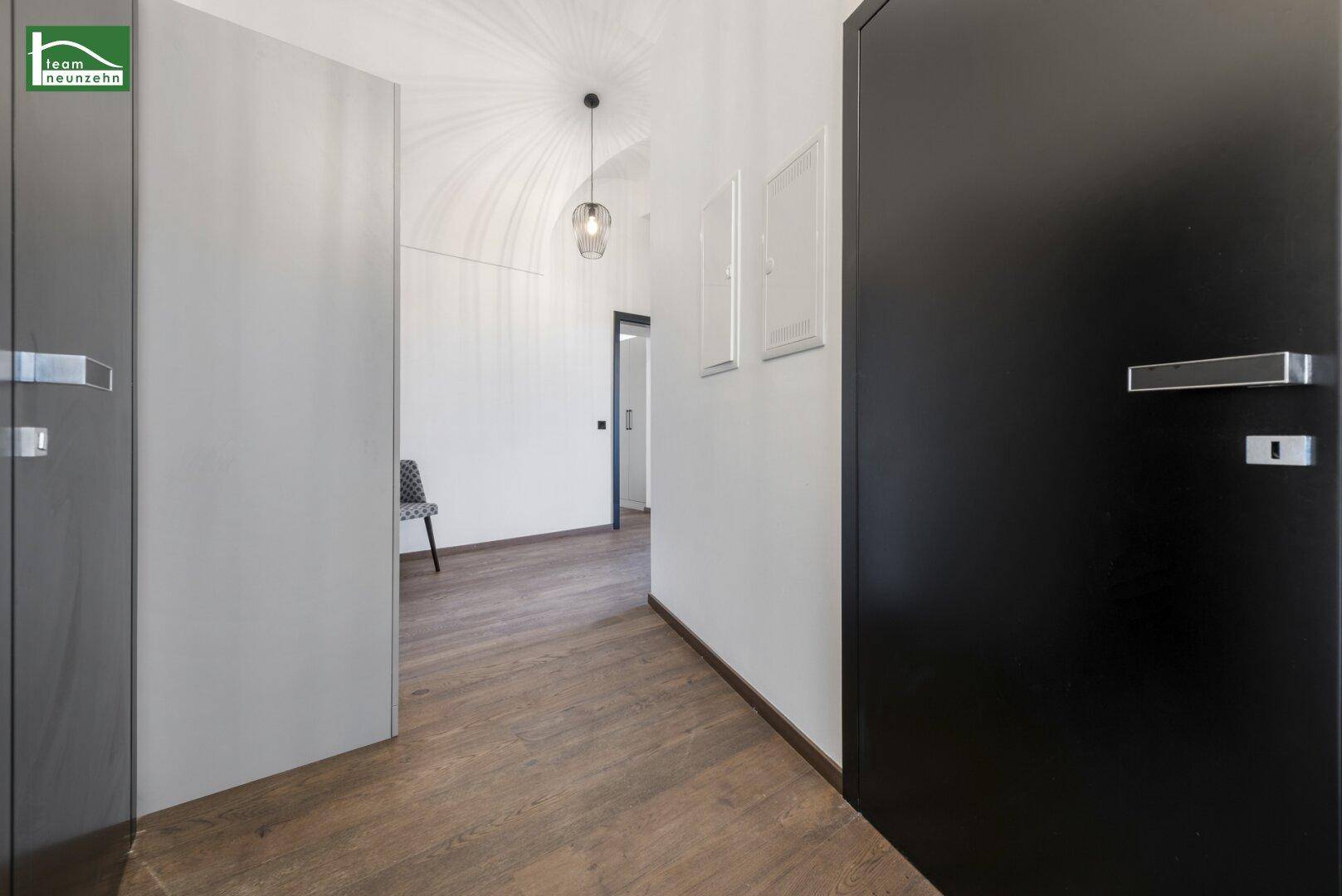 Heller Flur mit Holzboden und modernen Türen, der zu weiteren Räumen führt.