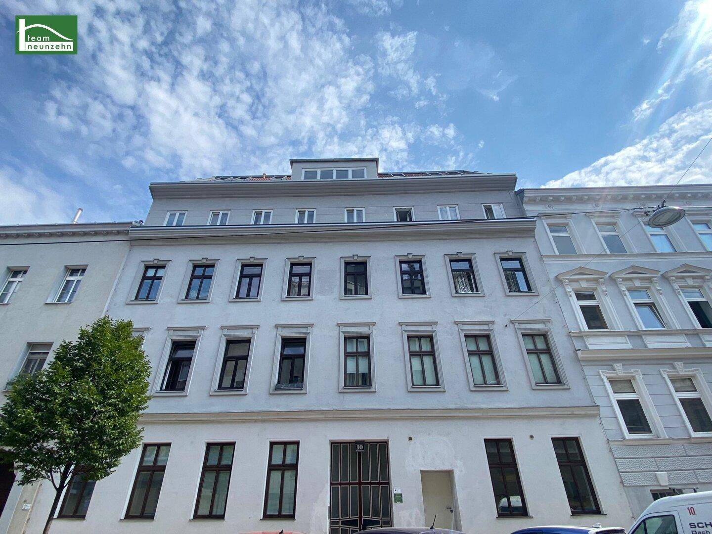 Klassische Fassade eines Mehrfamilienhauses mit modernem Dachausbau und Photovoltaikanlage.