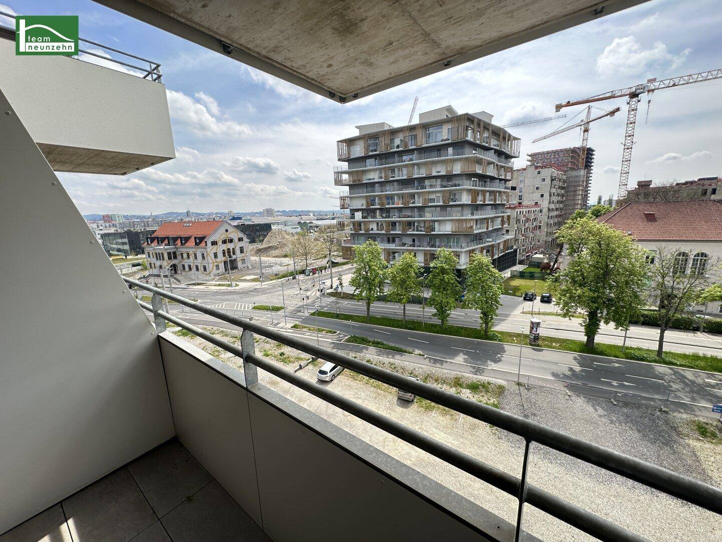 Balkon mit Blick auf die Straße und umliegende moderne Gebäude in städtischer Umgebung.