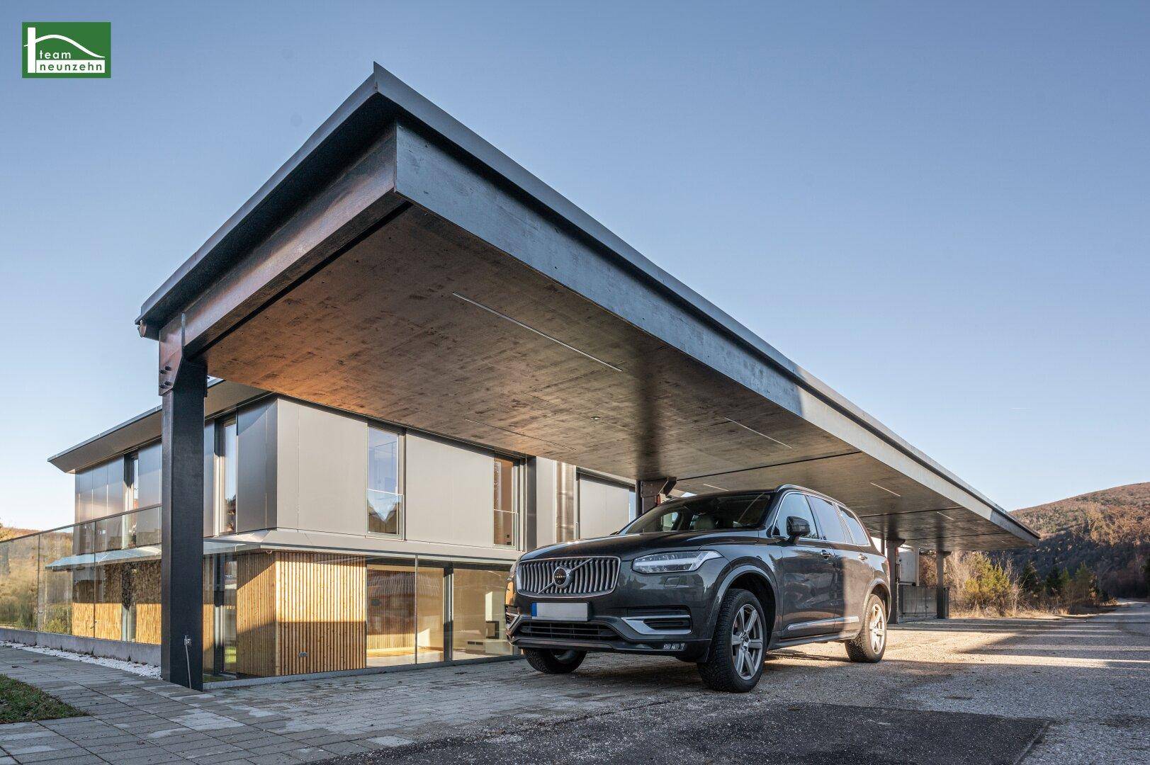 Moderner Carport mit Flachdach und integriertem Stellplatz vor dem Wohngebäude.