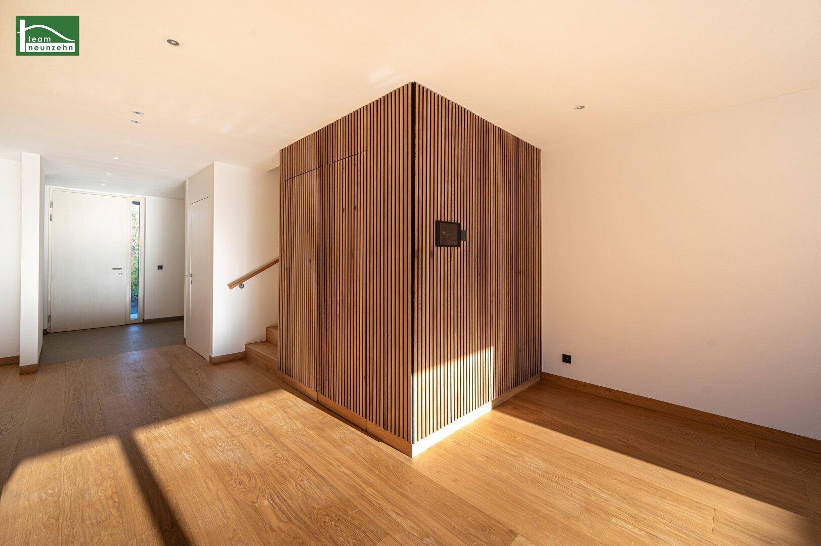 Geräumiger Eingangsbereich mit Holzboden, moderner Holzvertäfelung und viel Tageslicht.