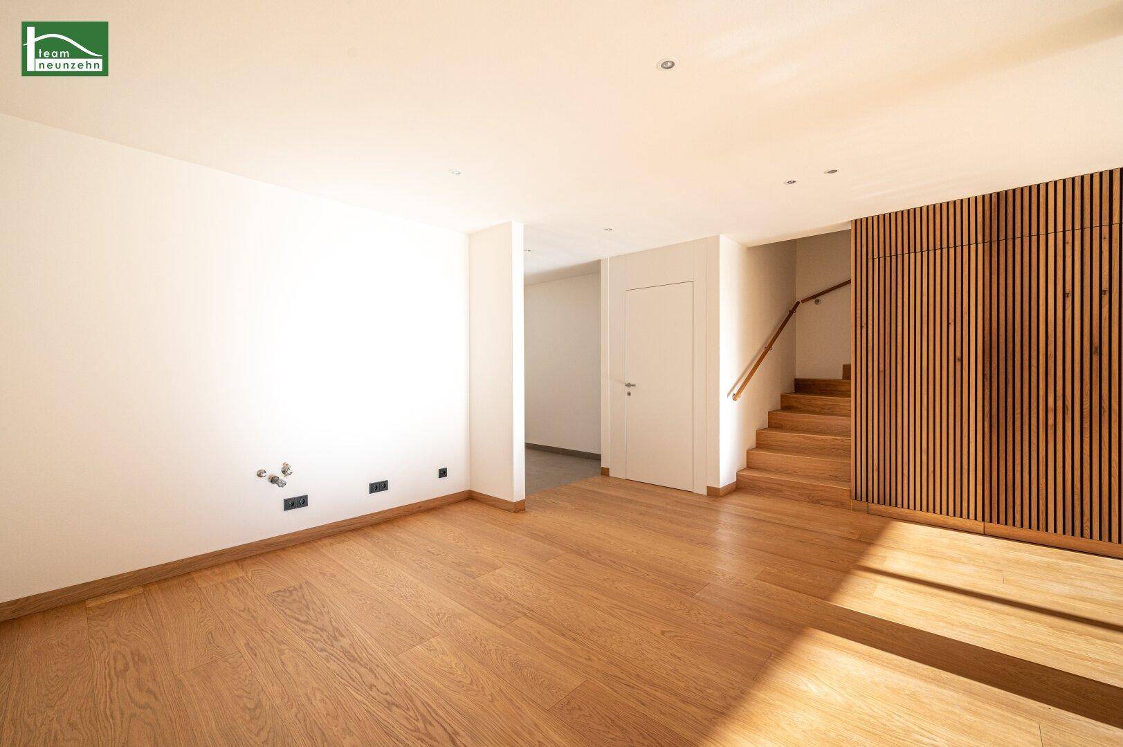 Geräumiger, heller Raum mit Holzboden, Holzvertäfelung und Zugang zu einer Treppe.