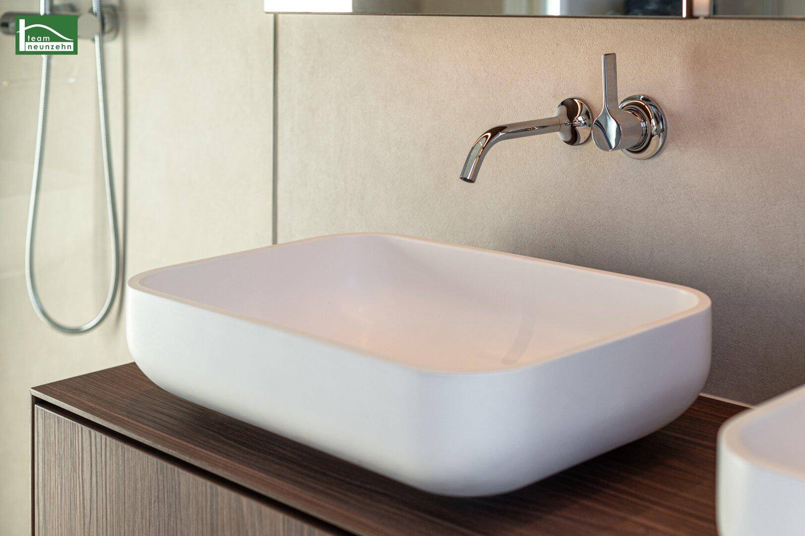Modernes Einzelwaschbecken mit Wandarmatur und schlichten Fliesen im Badezimmer.