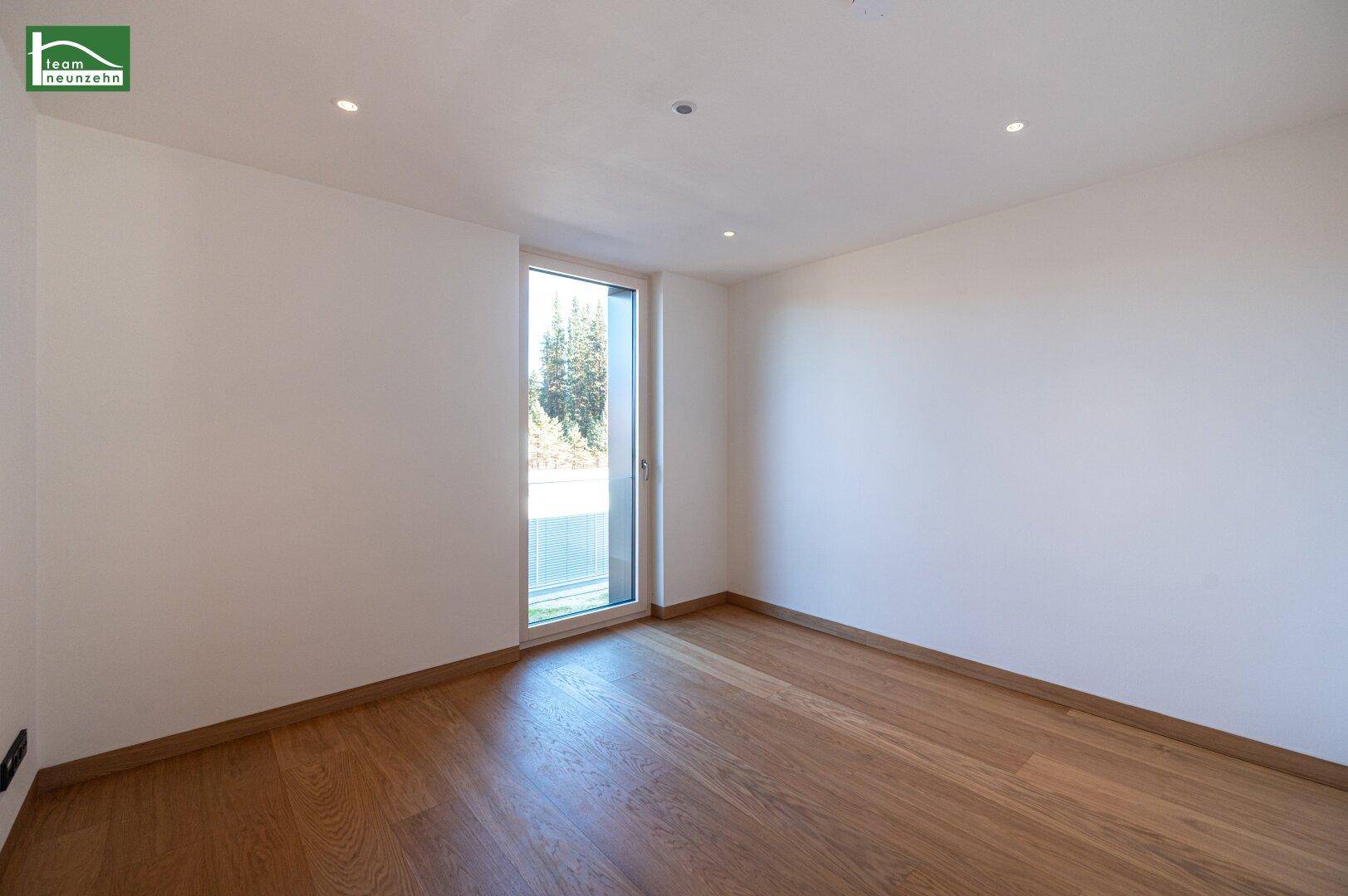 Helles Schlafzimmer mit Holzboden und Zugang zu einem möglichen Balkon oder Garten.