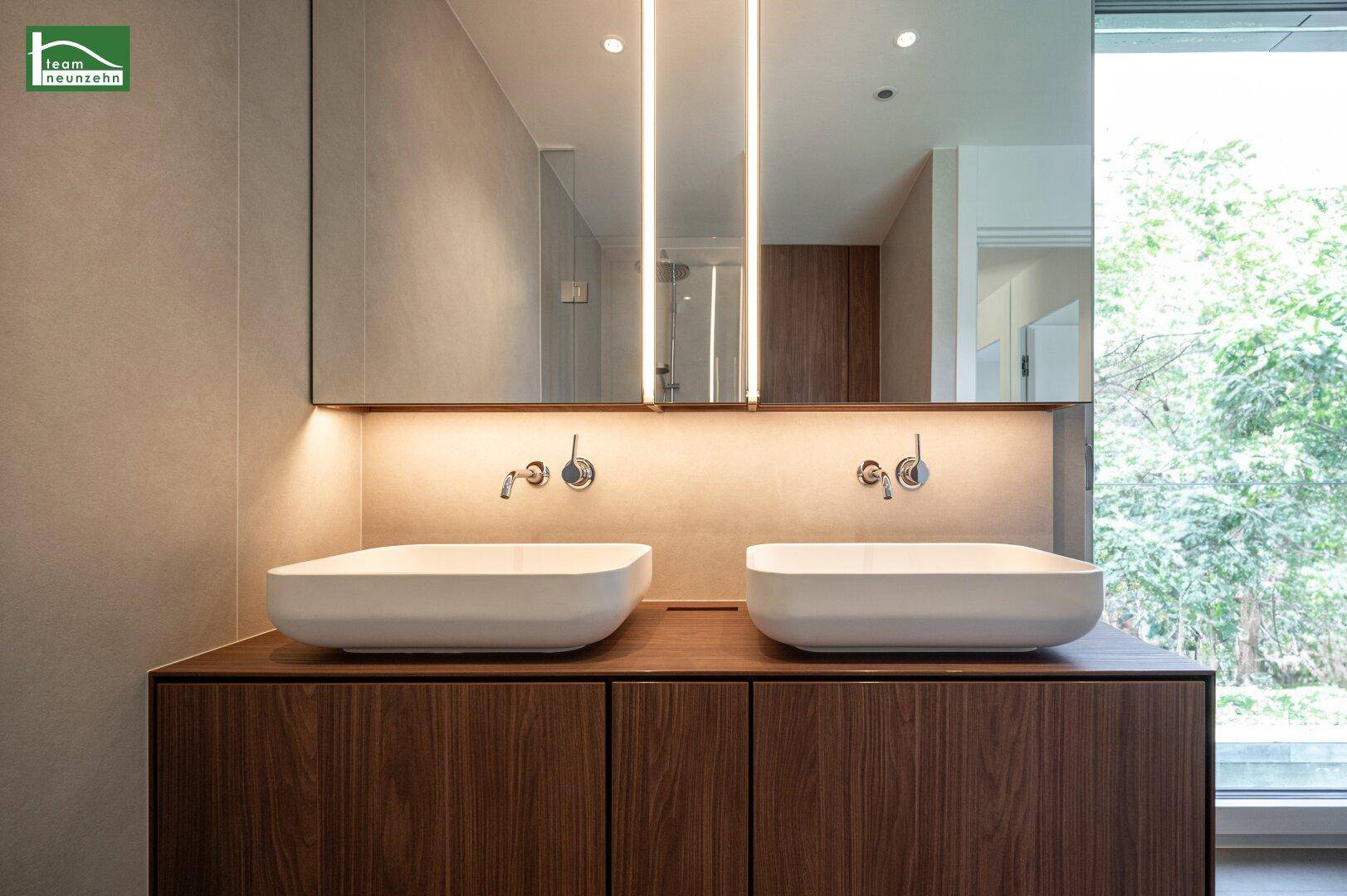 Modernes Badezimmer mit Doppelwaschbecken und großem Spiegel mit Beleuchtung.