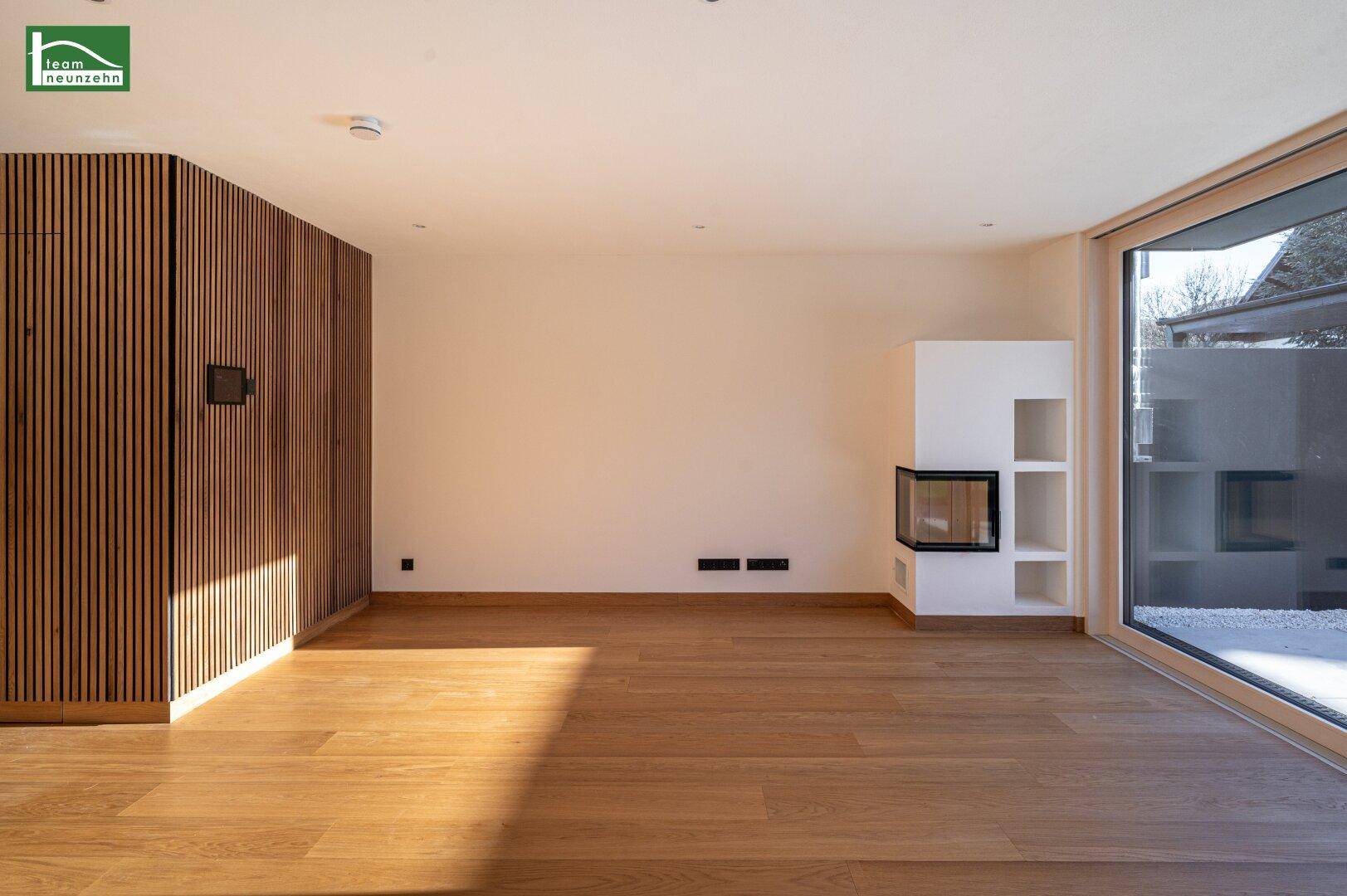 Lichtdurchfluteter Wohnbereich mit Holzboden und modernem Kamin als Blickfang.