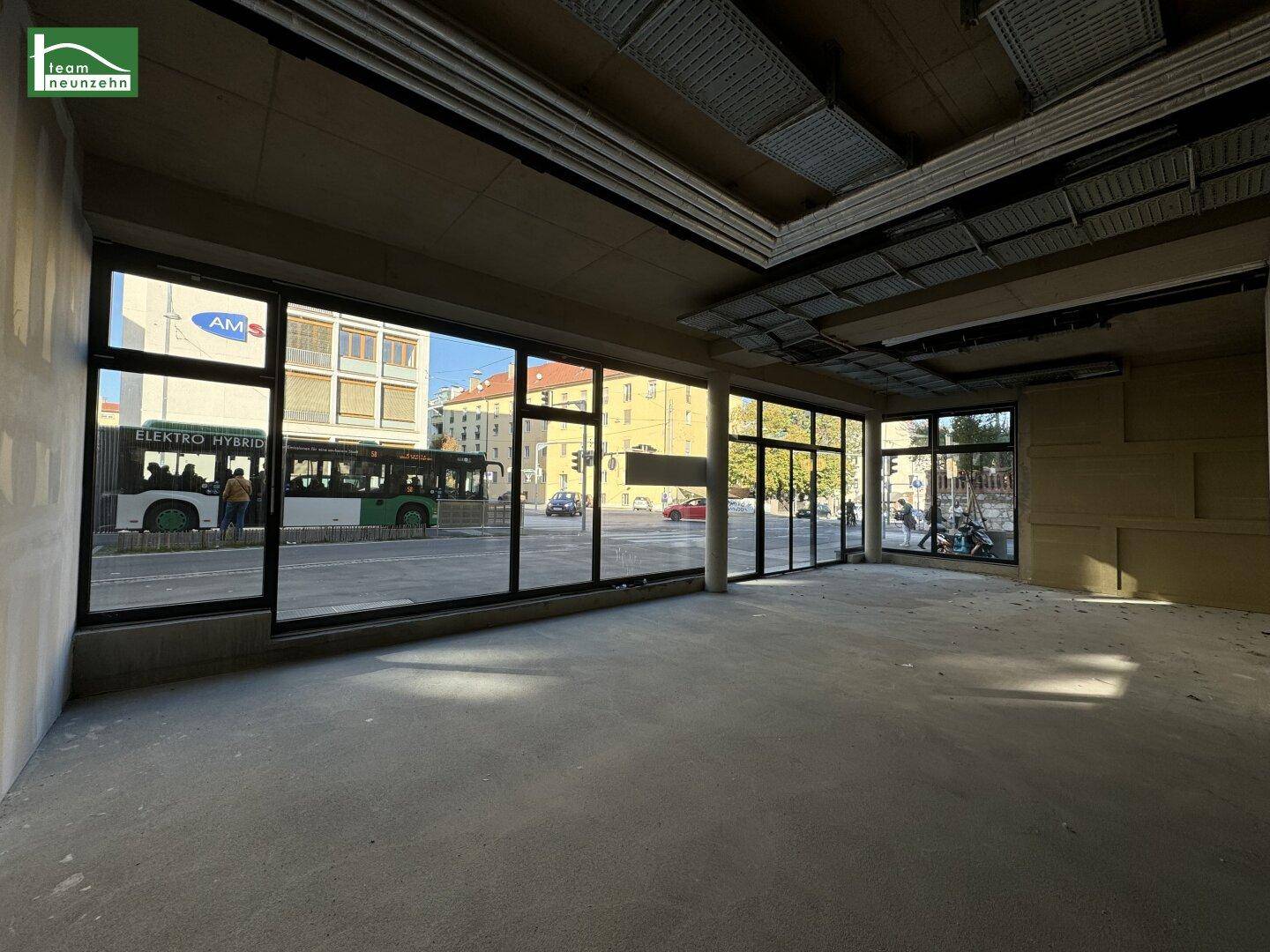Heller, unfertiger Gewerberaum mit großen Fenstern zur Straße, ideal für Ladenflächen oder Büros.