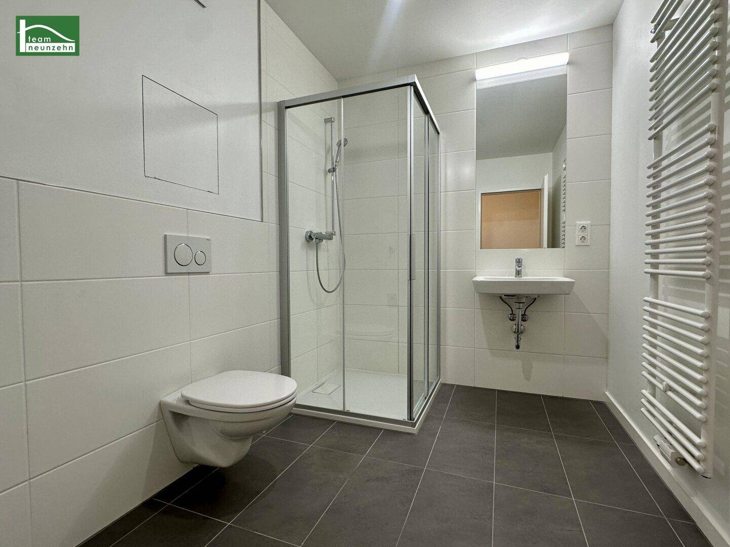 Modernes Badezimmer mit Duschkabine, wandhängendem WC und beheiztem Handtuchhalter.