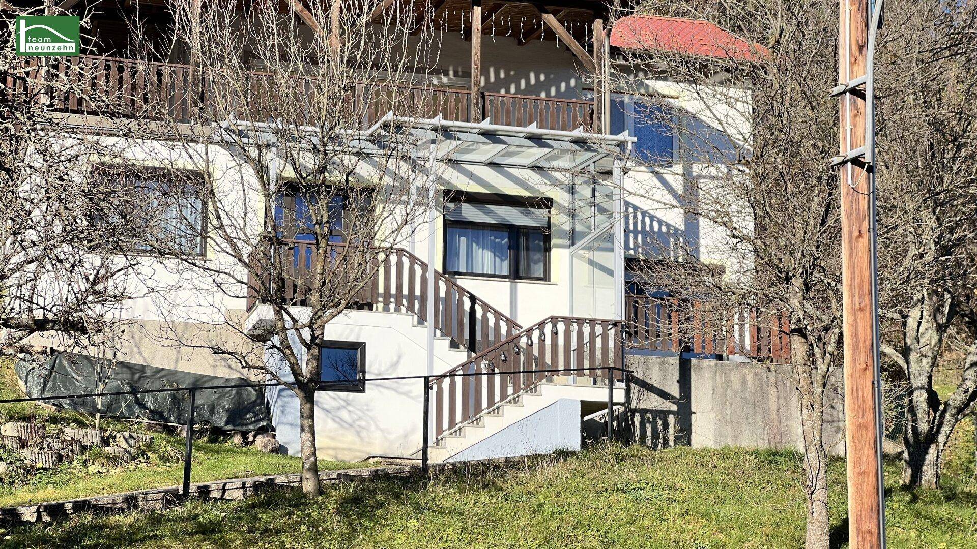 Ansicht des Hauses mit überdachtem Außentreppenaufgang und Balkon in ländlicher Umgebung.
