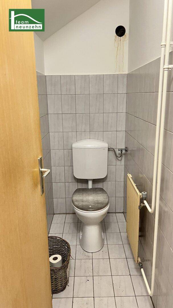 Separate Toilette mit hellen Fliesen und Heizkörper, einfach und funktional.