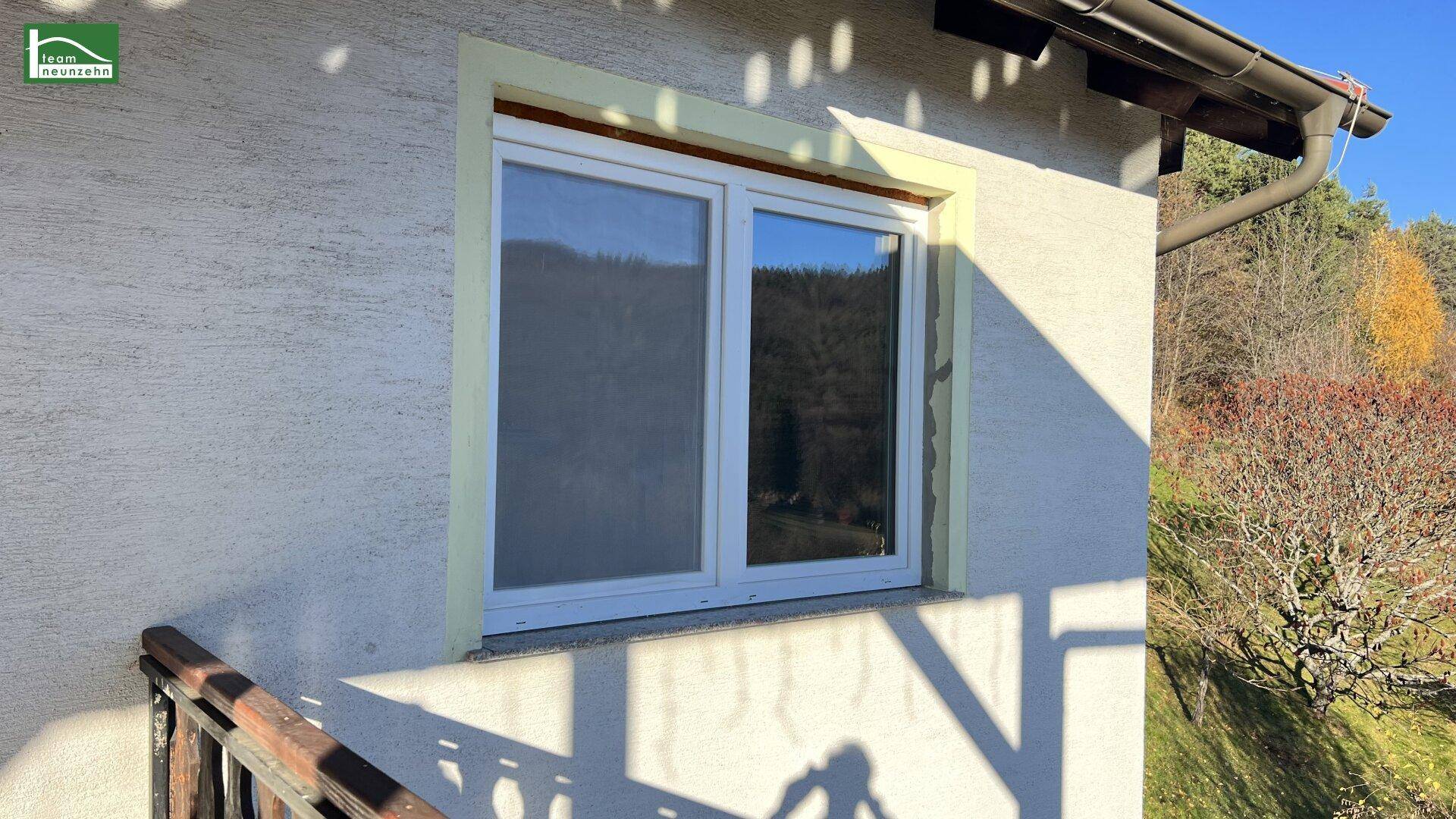 Fensterdetail an der Hausfassade mit Blick auf die umliegende Natur.